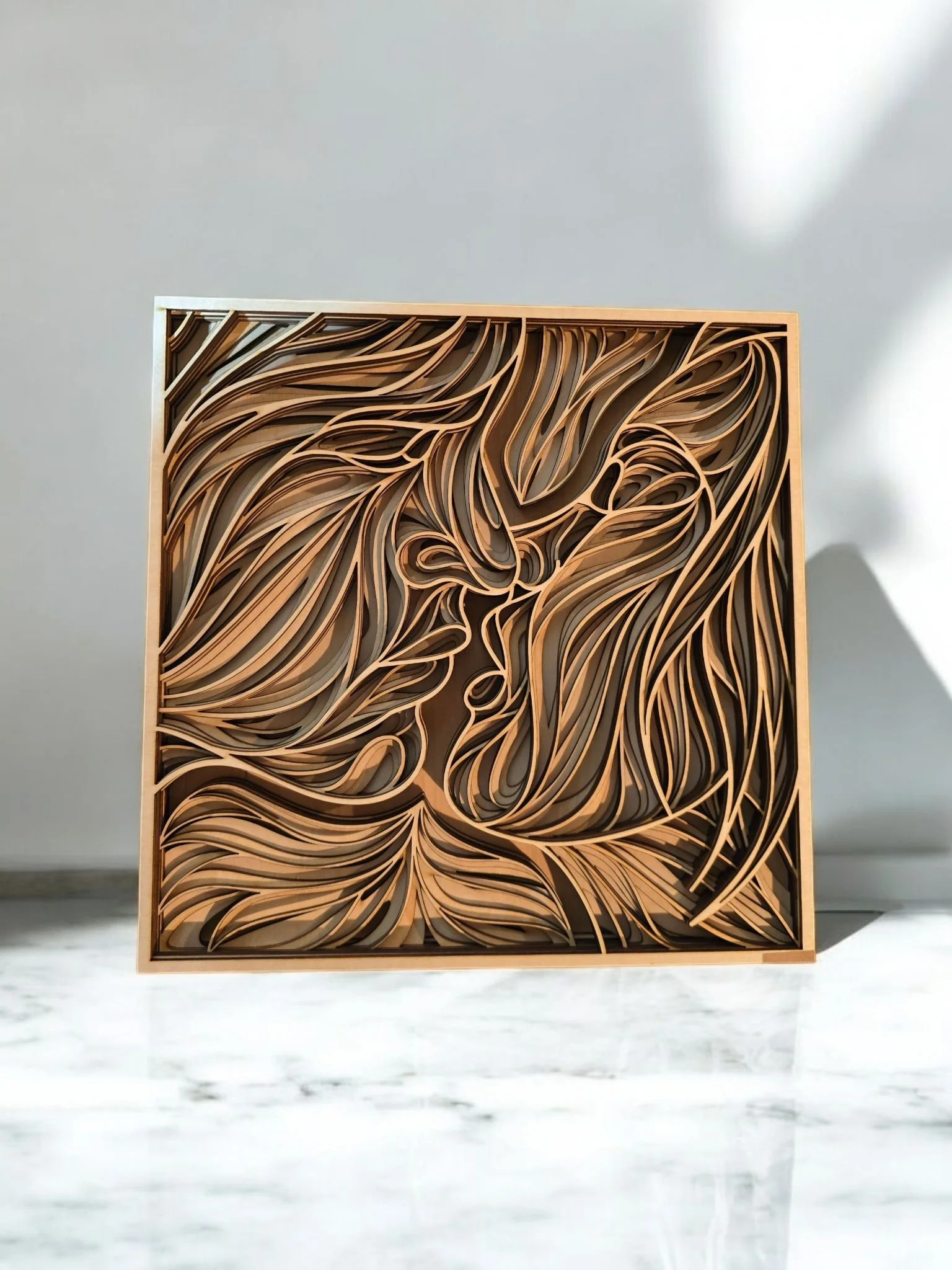 Wooden art piece with intricate swirls and a face in profile, set against a neutral background.
