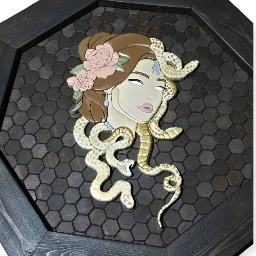Decorative wall art of a mermaid with flower and butterfly details, featuring a snake and tentacles in a black hexagon-tiled shadow box.