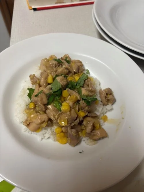 Picture of a stir-fried chicken and corn dish served over rice and garnished with cilantro
