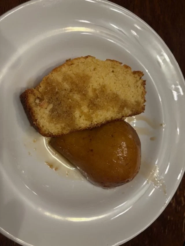 A slice of pound cake and a half of a pear, drizzled with maple sauce.