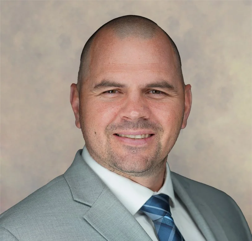 Professional headshot of a bald man in a light gray suit, white shirt, and blue striped tie, smiling against a neutral background. Certified Public Accountant, Tax advisor