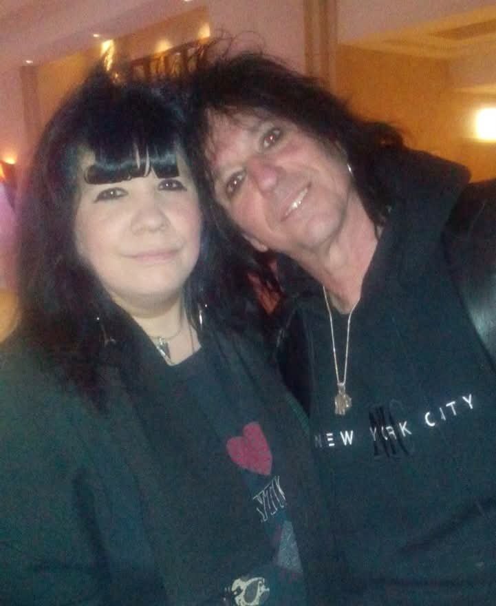 Two women with dark hair smiling for a photo, indoors with warm lighting.