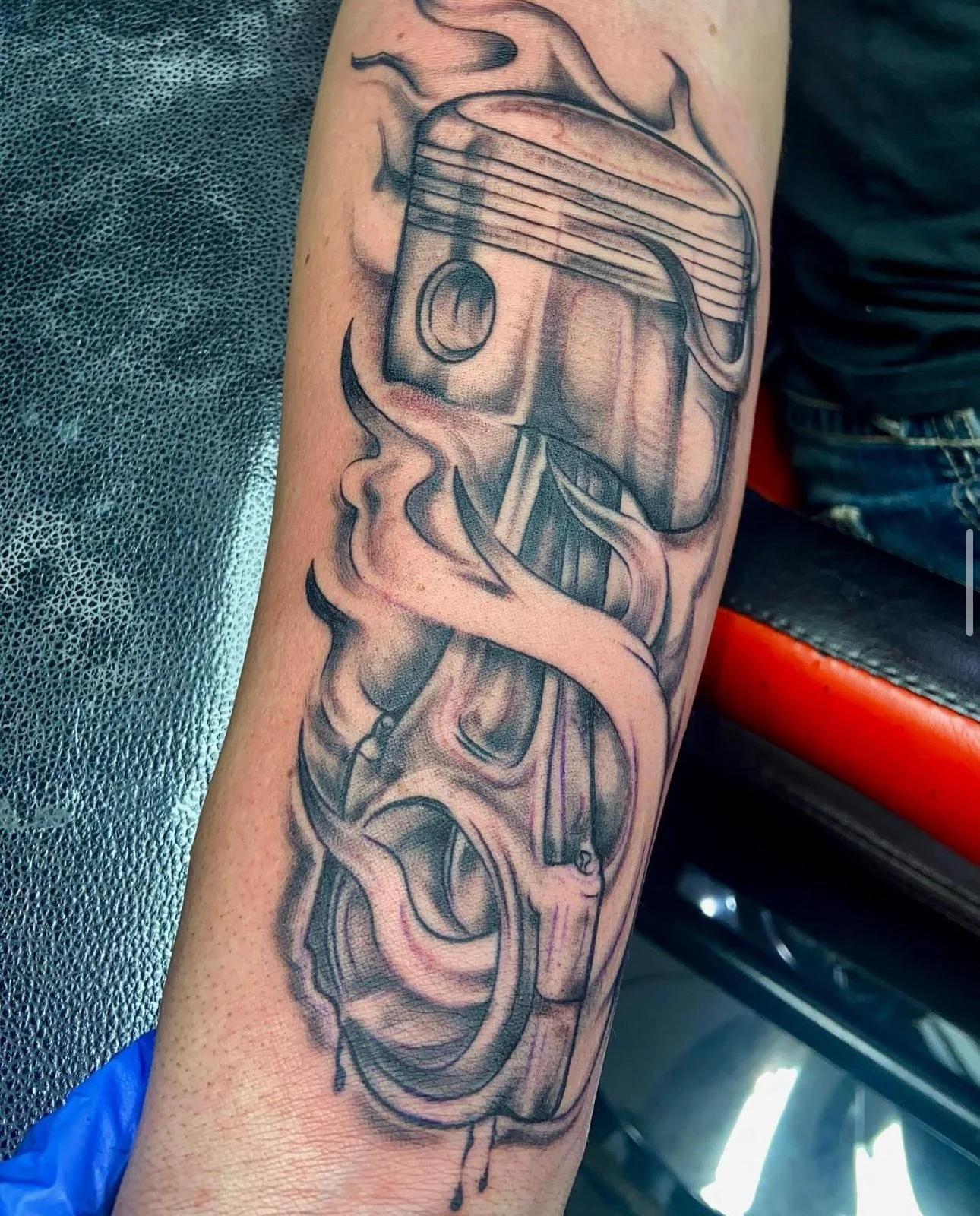Tattoo of a piston with steam or smoke and dripping ink on a person's arm.