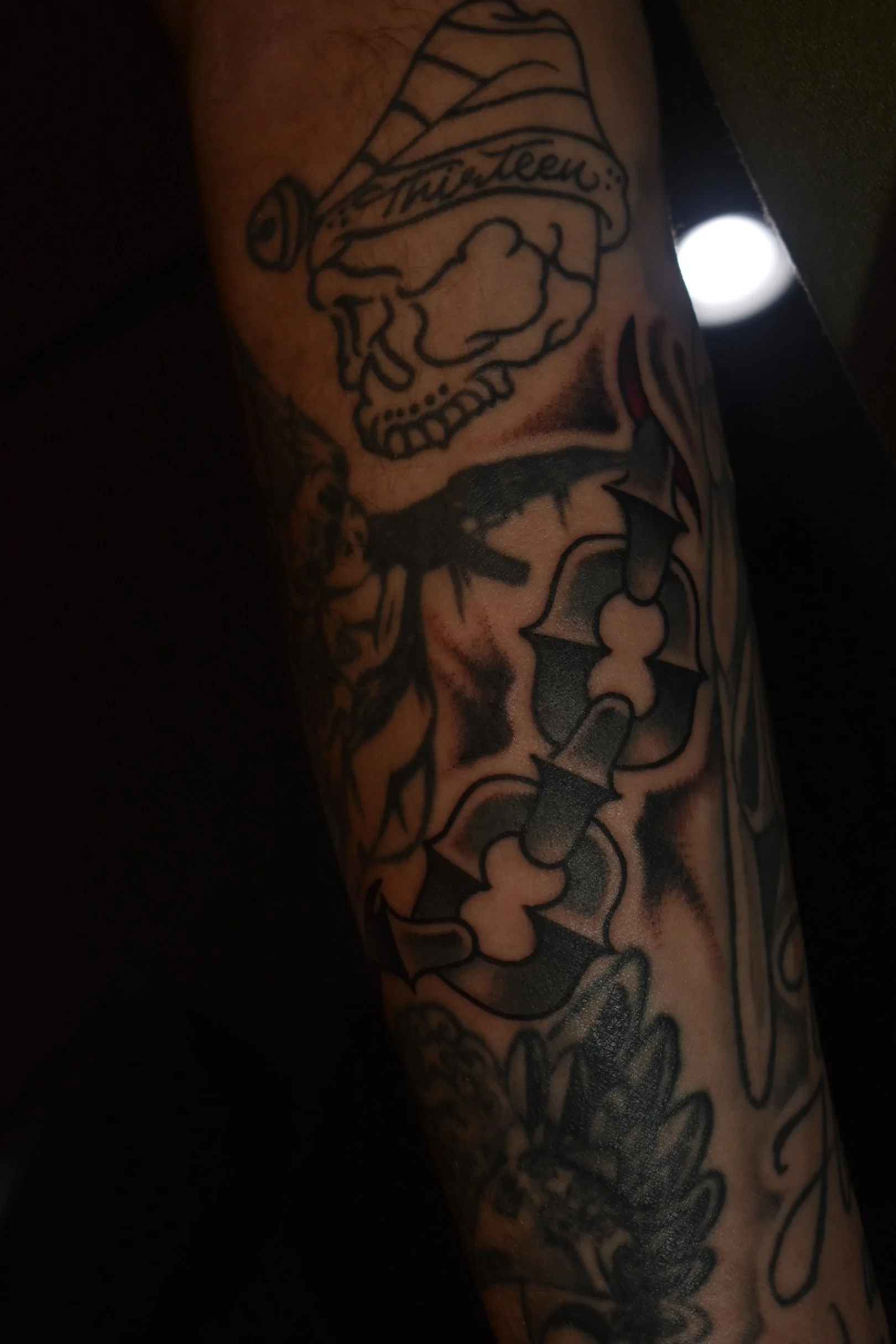 A tattoo of a skull wearing a Santa hat with the word "Muerte" written on it, and a bat with its wings spread.