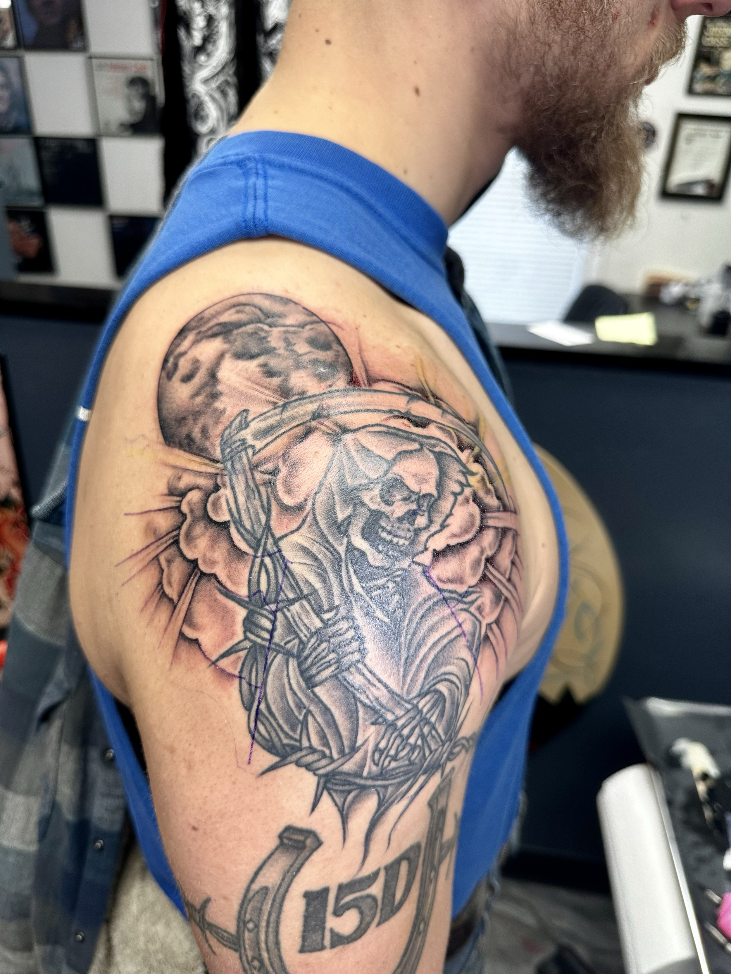 Tattoo of a warrior with a lion's head, holding a sword and shield, with a full moon in the background, and the number 15D beneath it.