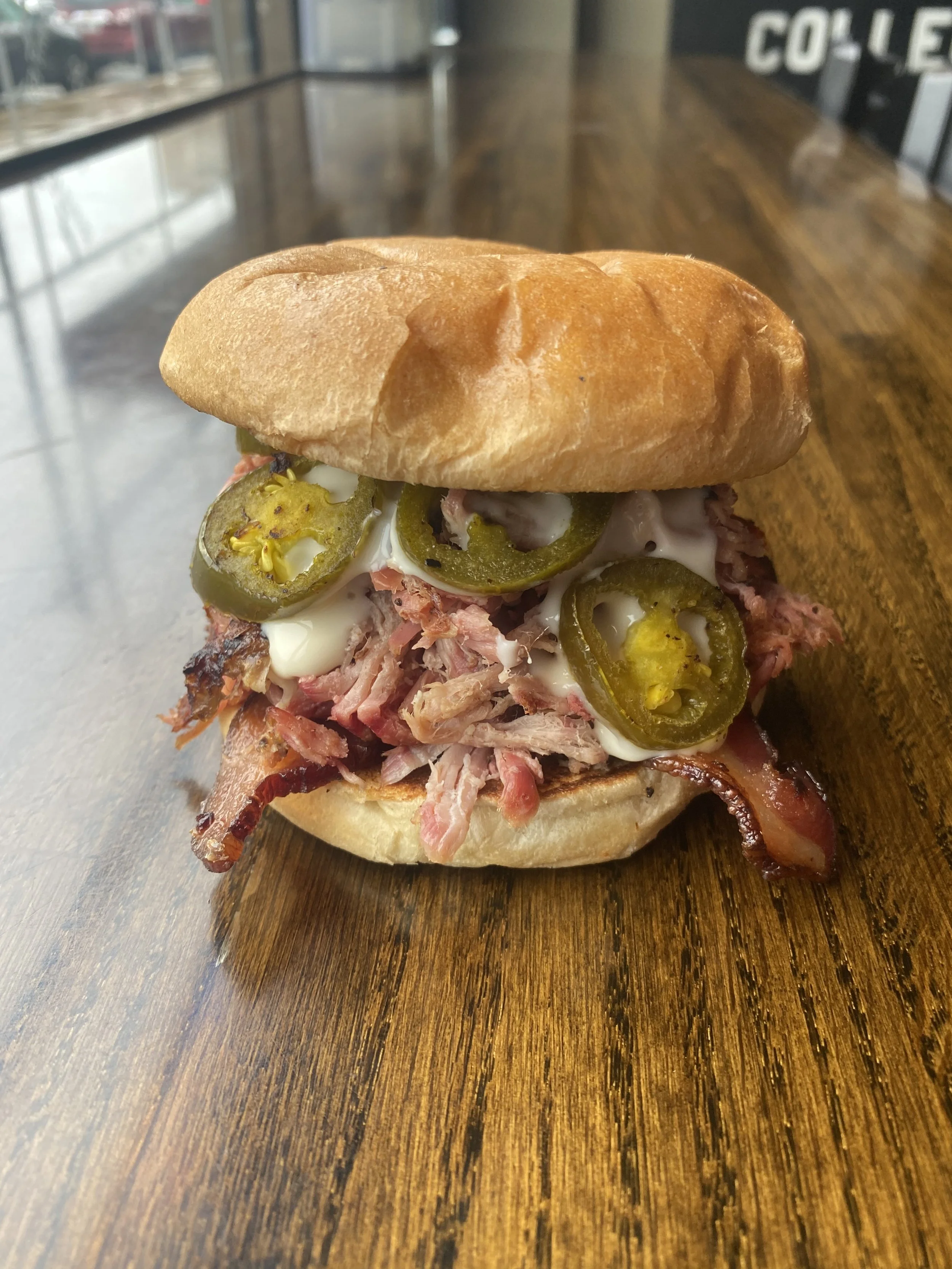 Big Pig Sandwich. Pulled Pork, Grilled Jalapeños, Thick Cut Baon, & Queso on a Toasted Bun
