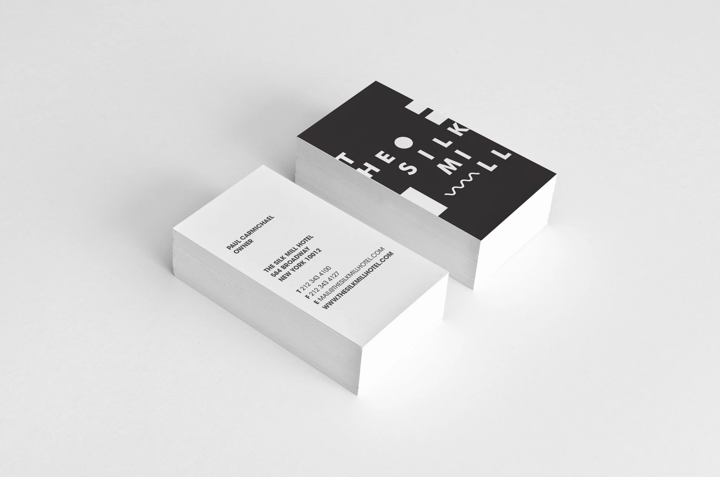 Business cards for The Silk Mill Hotel, featuring black and white designs, placed on a white background.