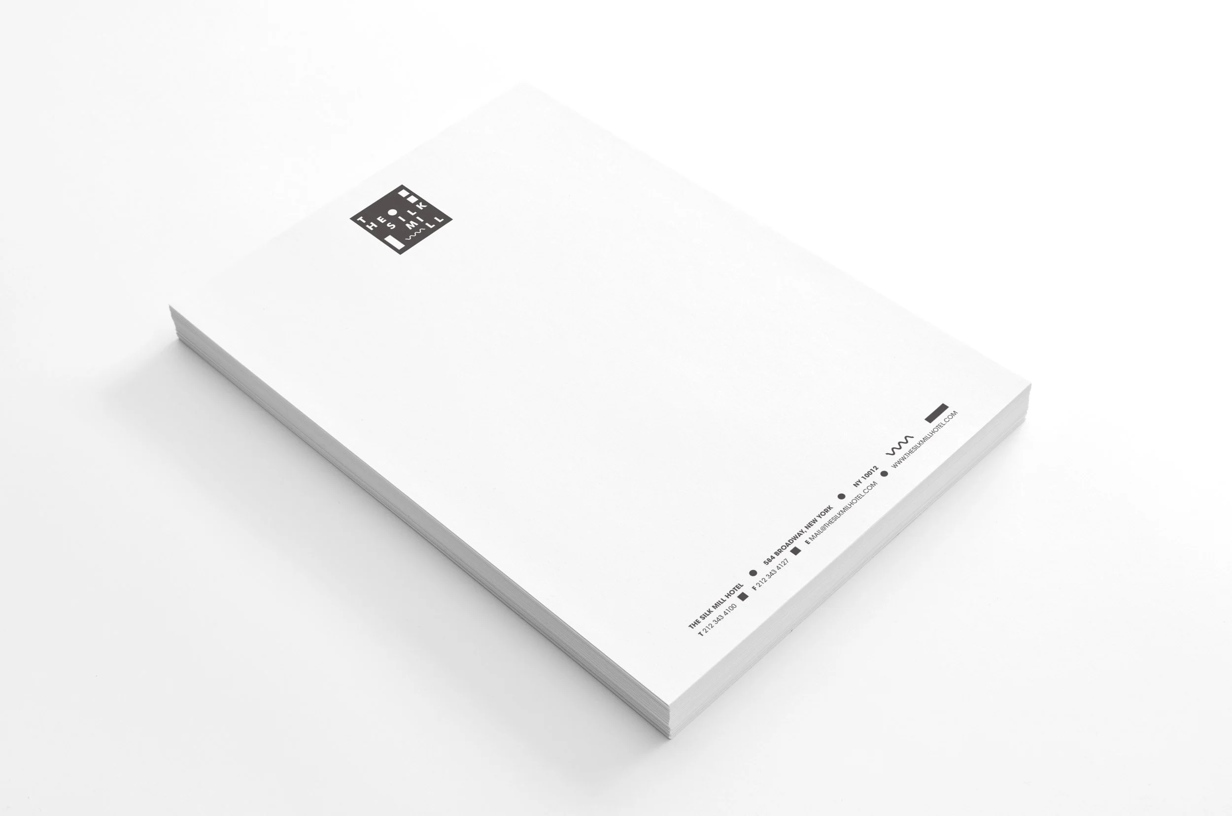 A white booklet with a small black logo on the top left corner and small text and icons at the bottom right corner.