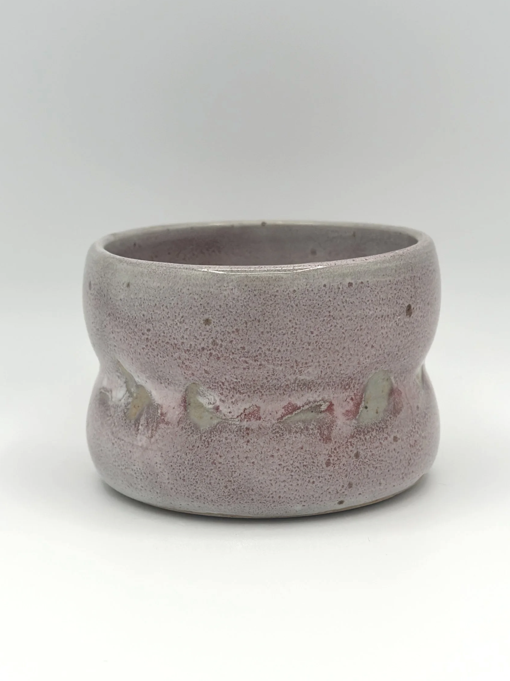 Handmade stoneware ceramic tumbler with 2 bubbles and a light grayish and pinkish candy coated shiny glaze