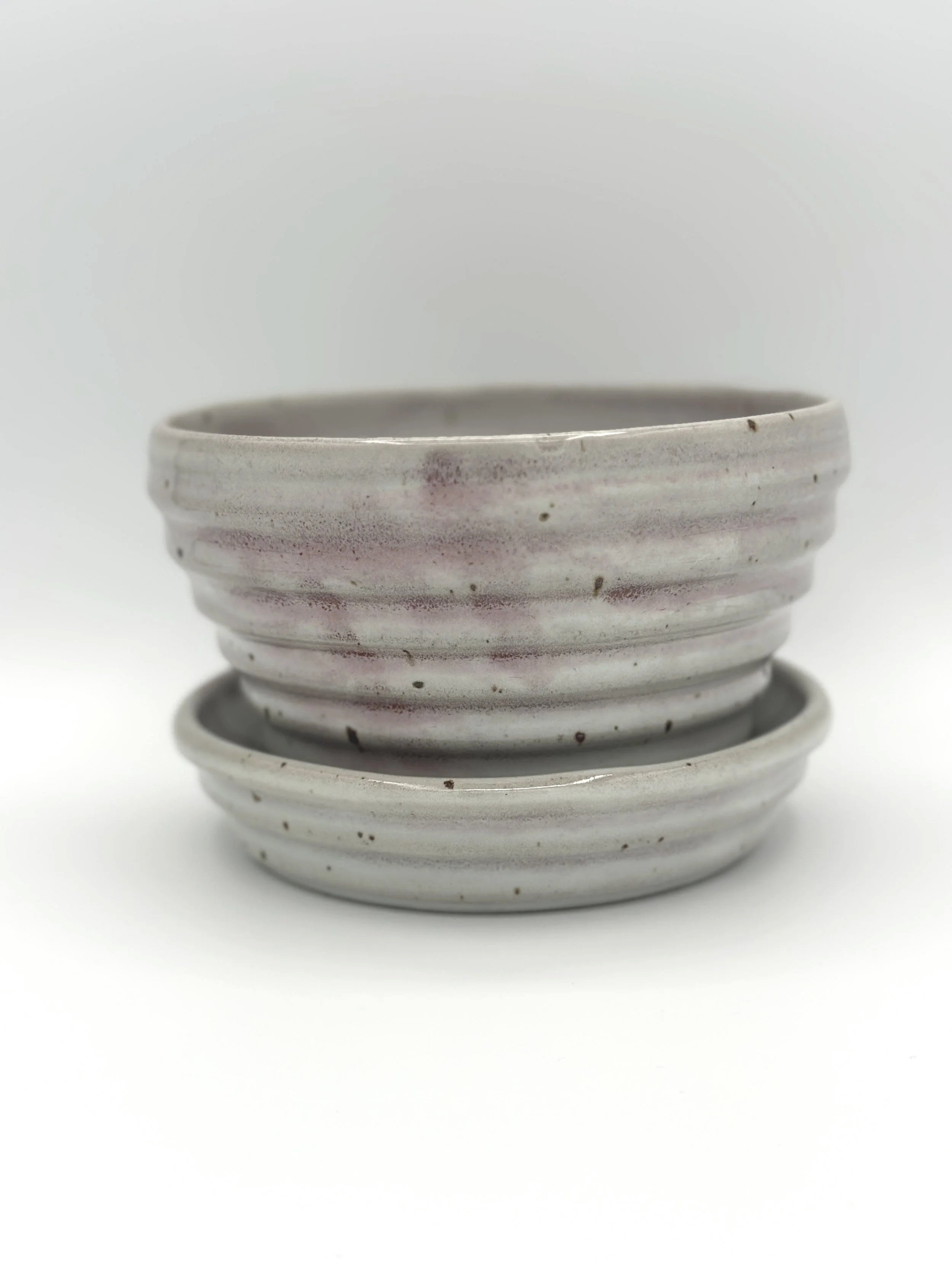 handmade stoneware ceramic planter with ribbed texture and tray. color is a deep mix of grey and pink with lots of motion and variability