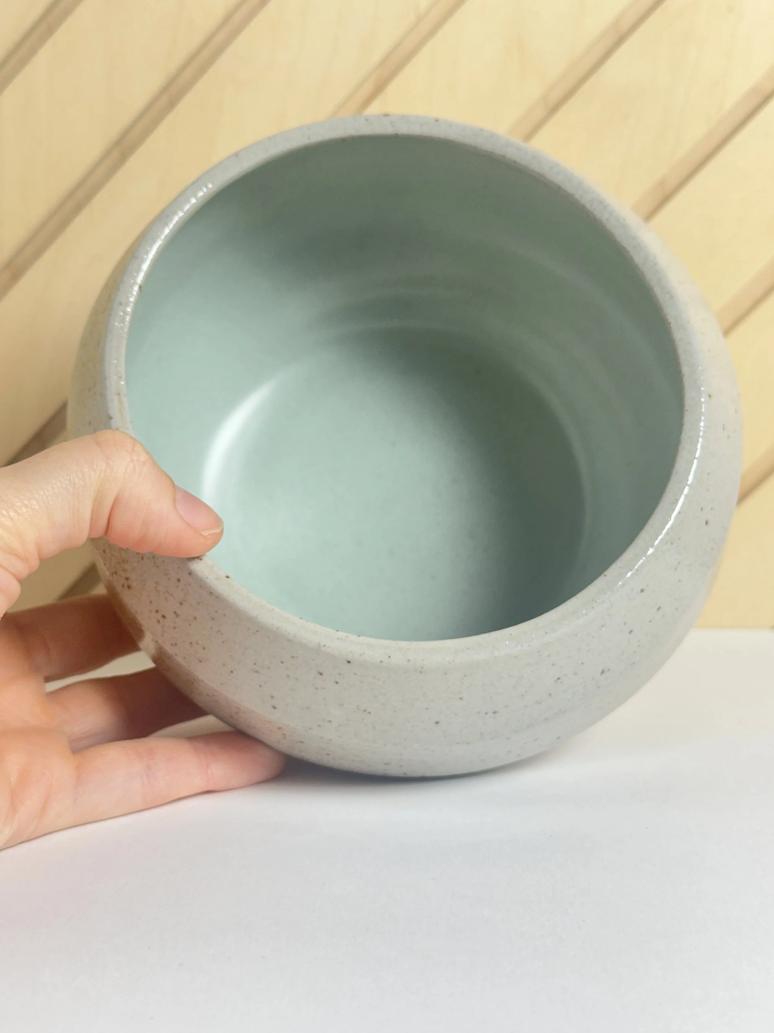 inside light blue satin bowl with a hand holding it