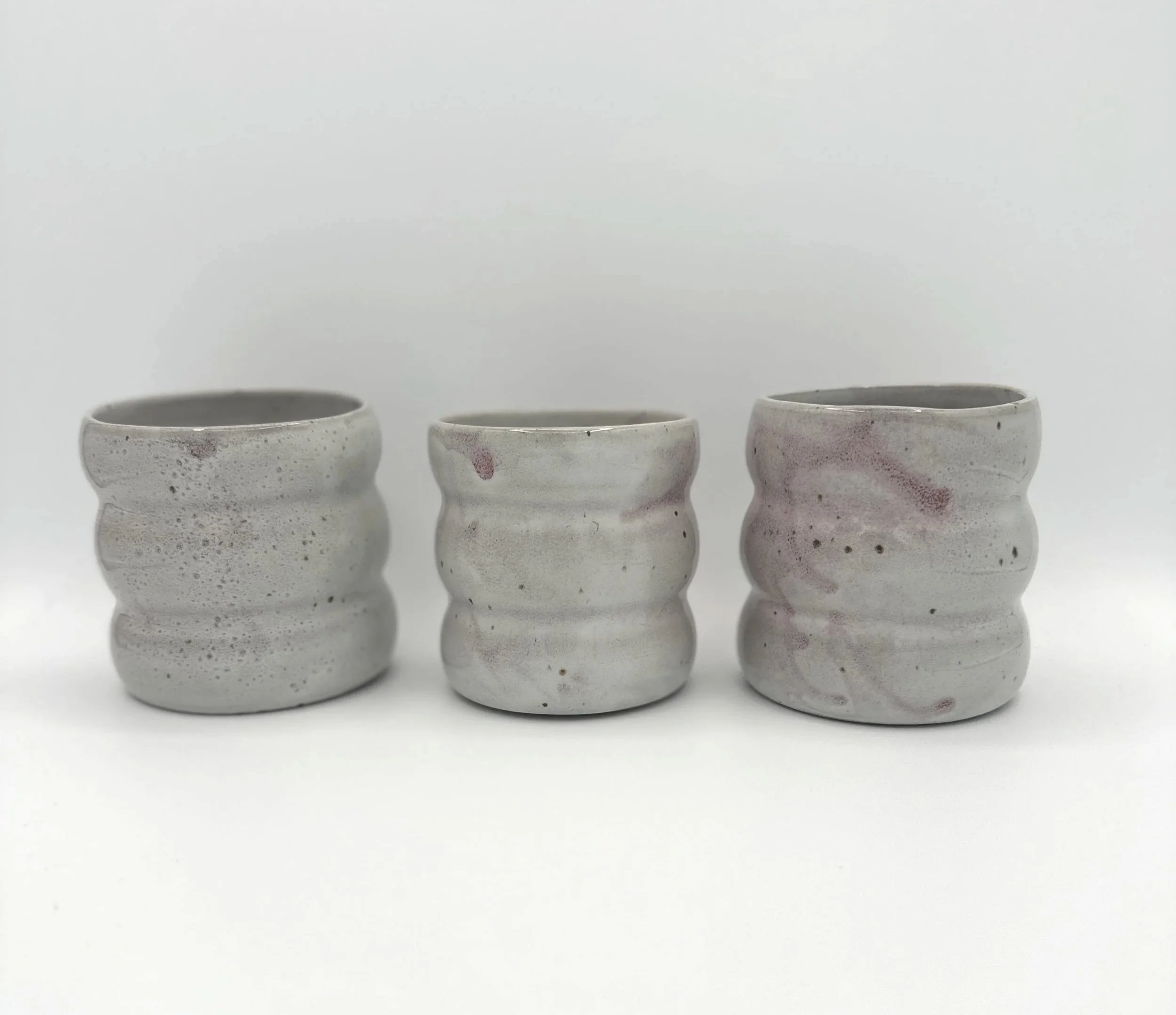 Handmade stoneware cup with dusty pink speckled glaze and pinched waist shape
