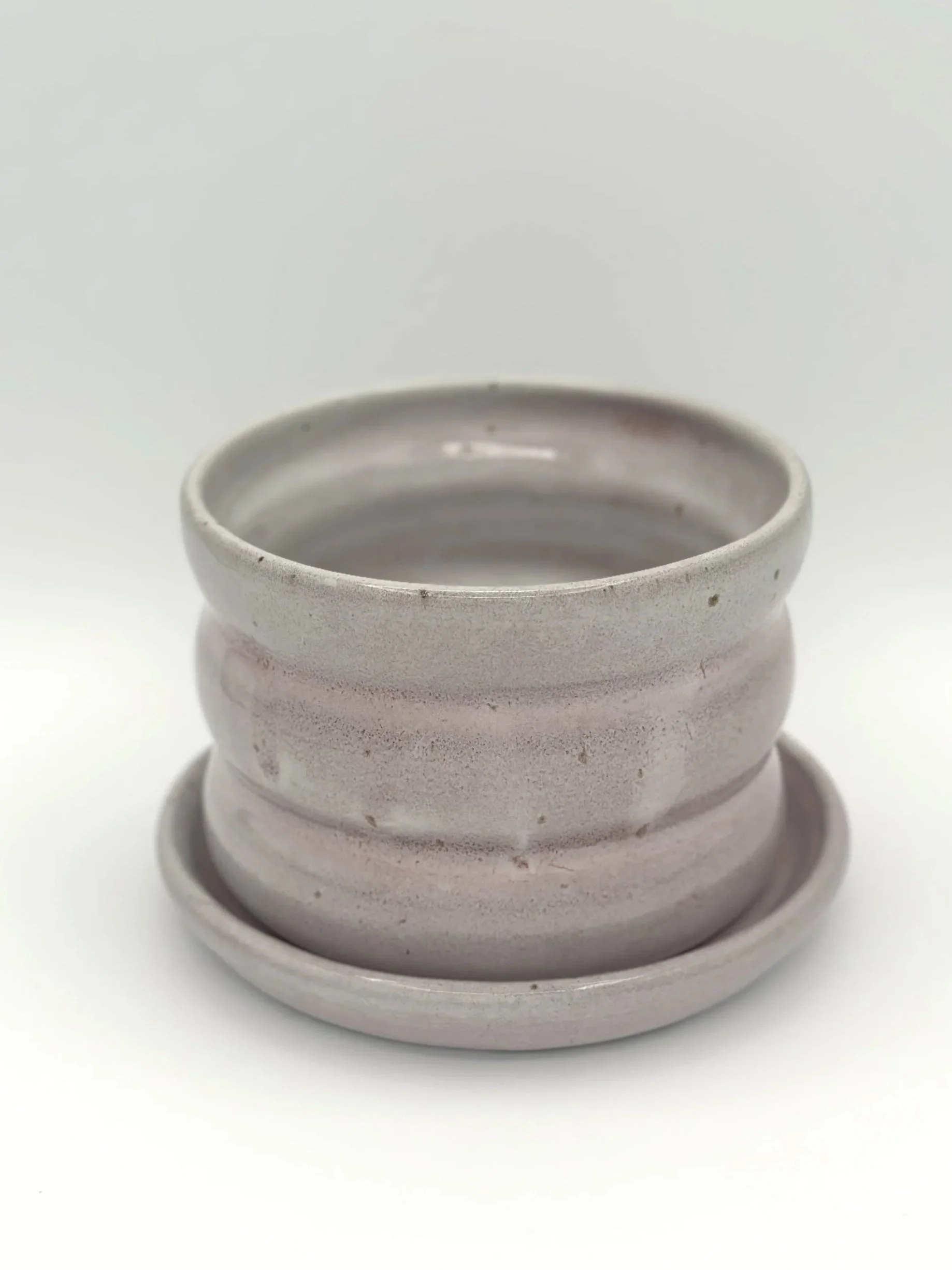 handmade stoneware ceramic bubble planter with 3 waves and a tray in glossy lavender, mauve, pink and grey glaze held by a manicured hand