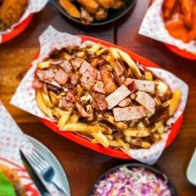 French fries topped with chopped steak and pieces of crispy bacon in a red basket.