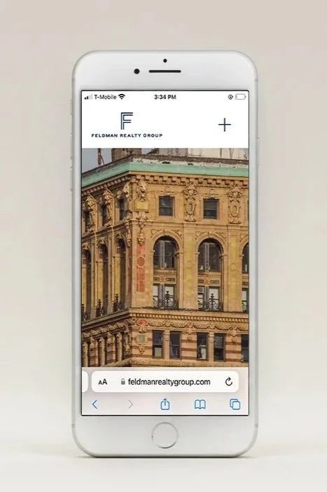 A white smartphone displays a real estate website with an image of an ornate historic building.