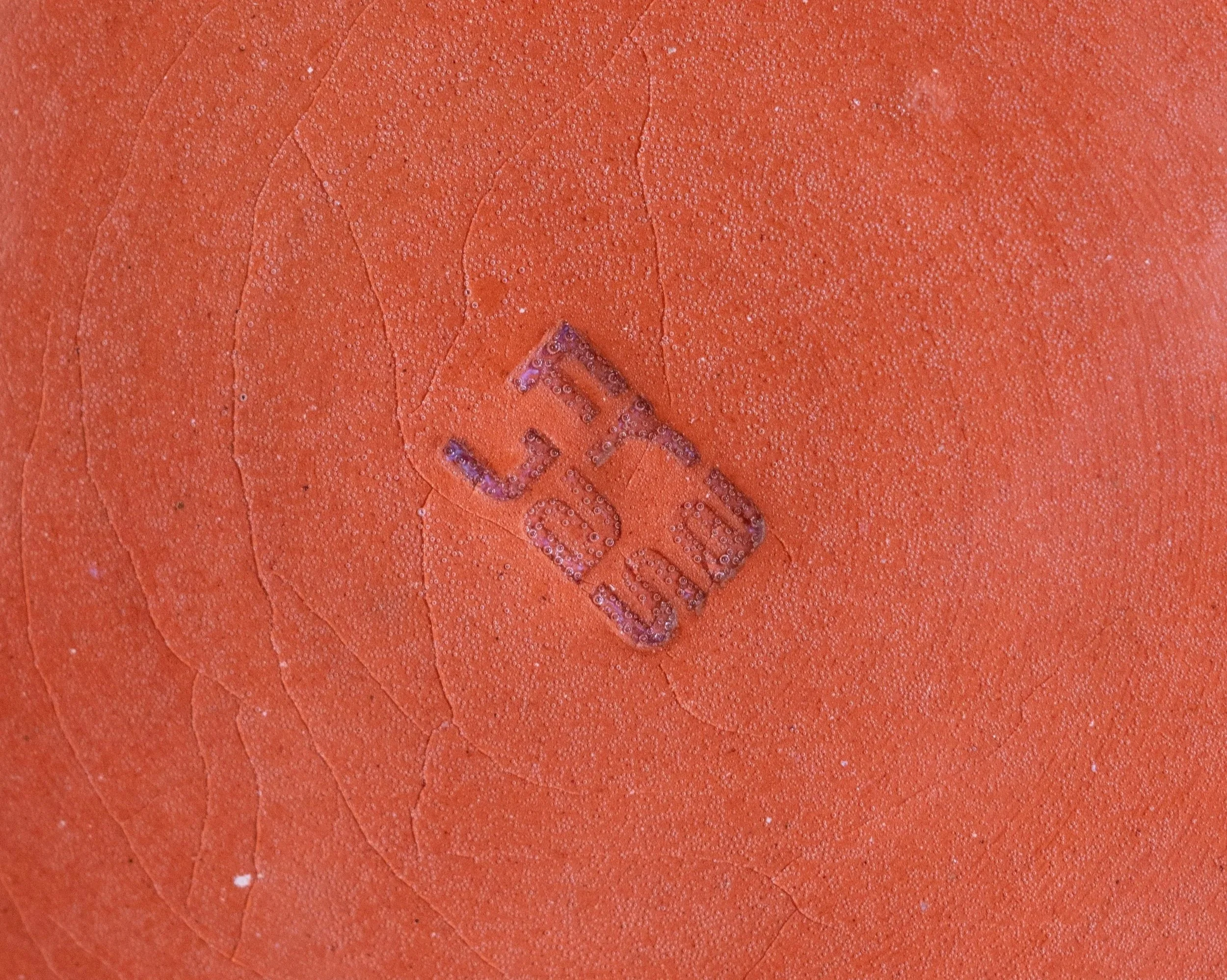 Close-up of an clay surface that has been stamped with the logo "FraJas".