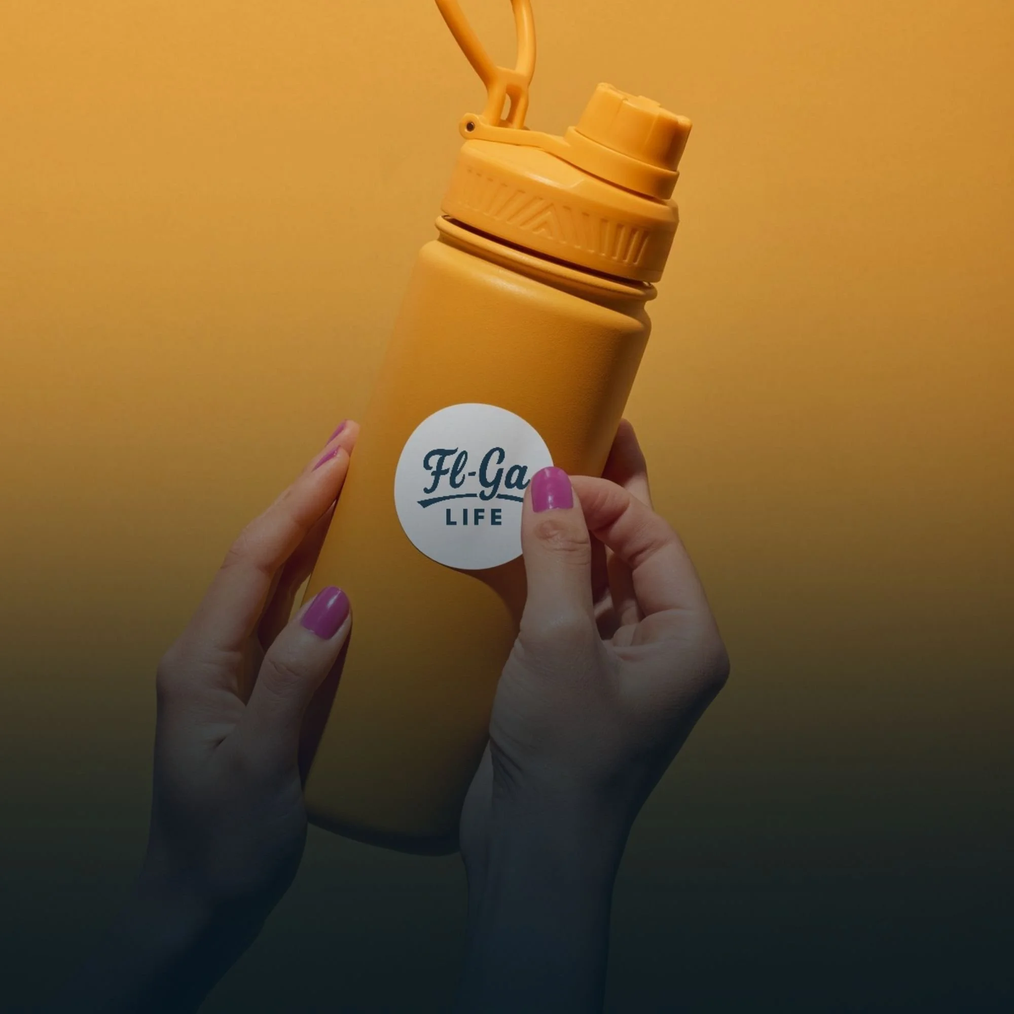 A person holding a yellow water bottle with a white circular label that reads 'Fl-Ga LIFE'. The bottle has an orange lid and is set against a gradient background from yellow to dark green.