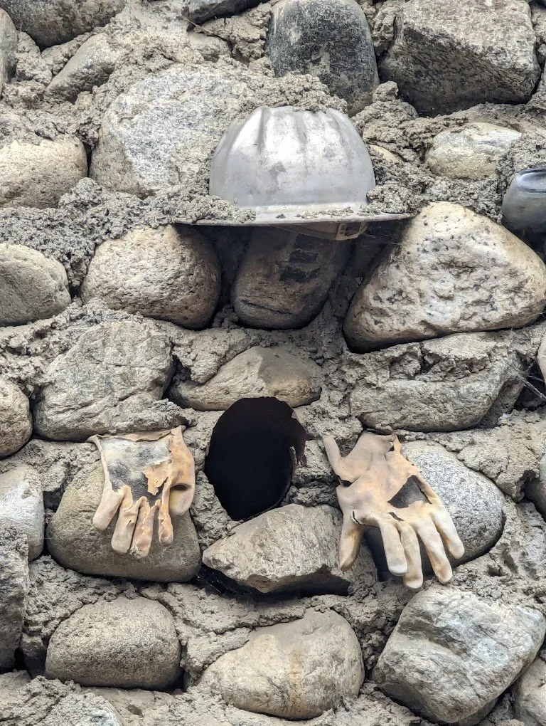 Stone wall at Rubel Castle with sculpted hands emerging from an opening.