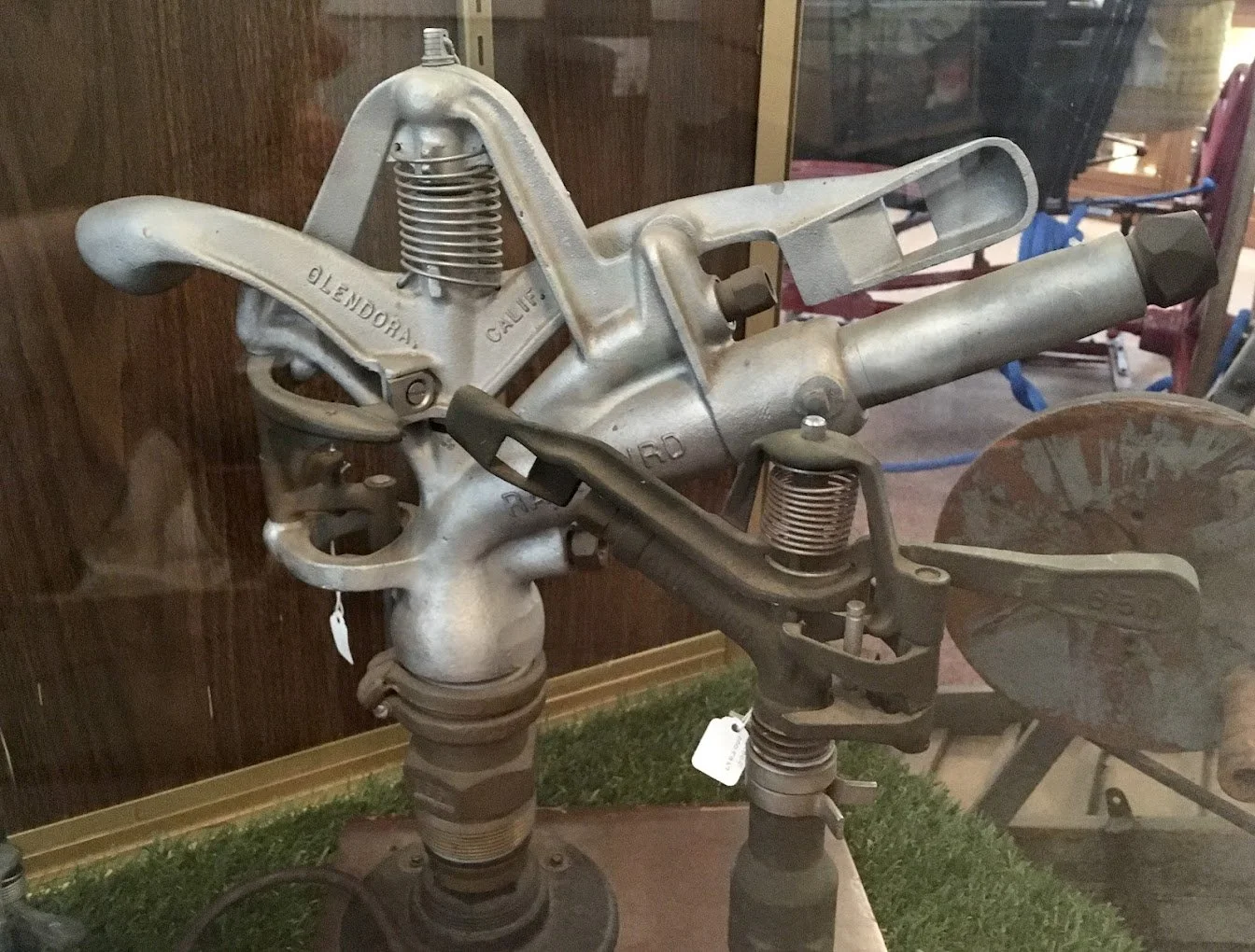 Vintage sprinkler and components on display, including parts with labeled 'Glendora' and 'Calif'.