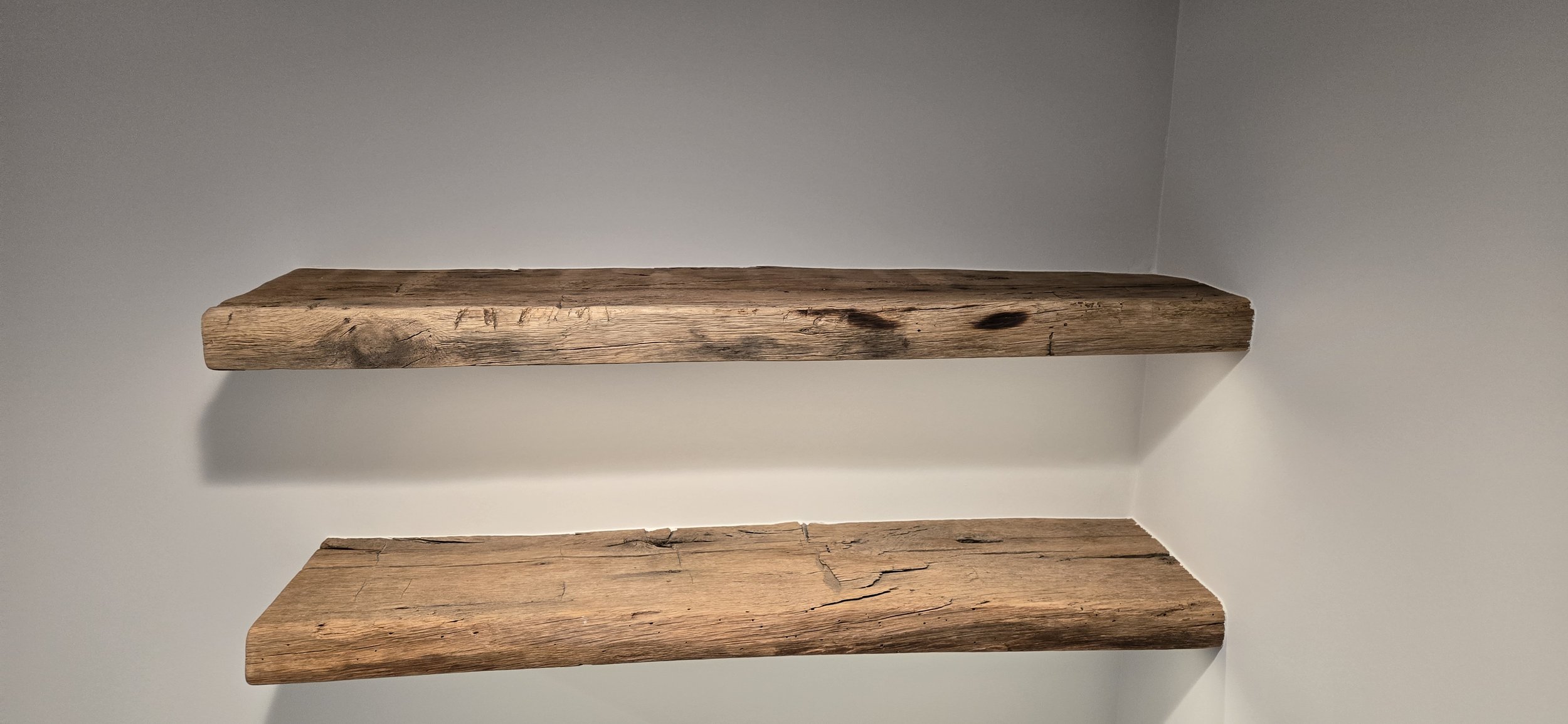 Two rustic wooden shelves mounted on a white wall.