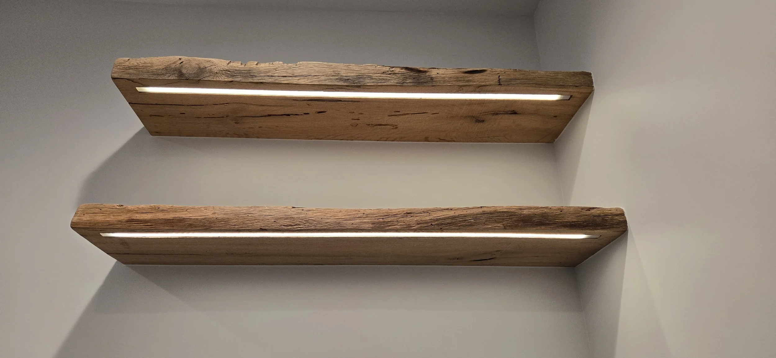 Two rustic wooden shelves mounted on a white wall with built-in LED lighting.