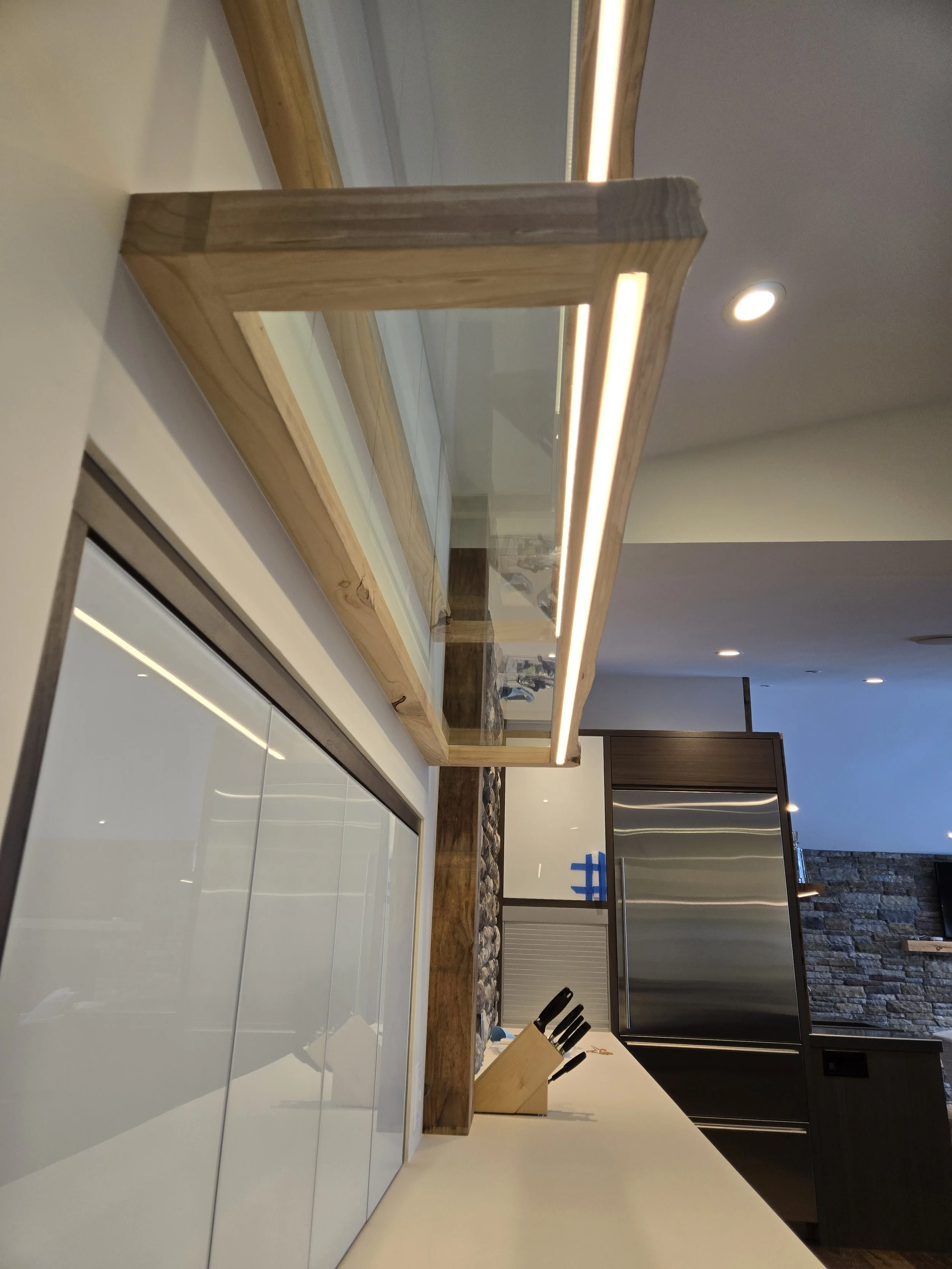 Modern kitchen with white cabinets, wooden countertop, knife set, stainless steel appliances, and stone accent wall.