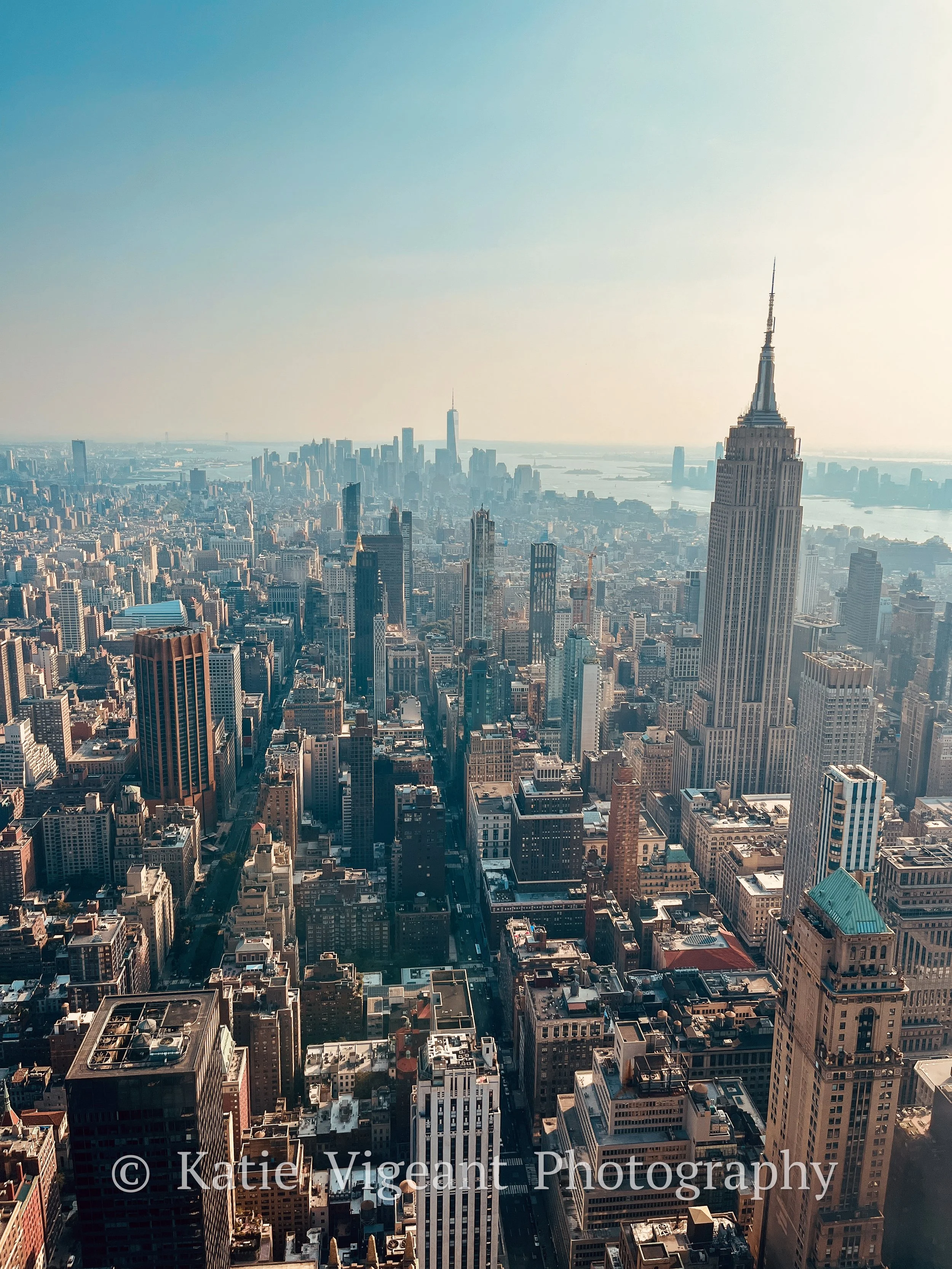Aerial view of New York City skyline with the Empire State Building in the foreground and One World Trade Center in the background.