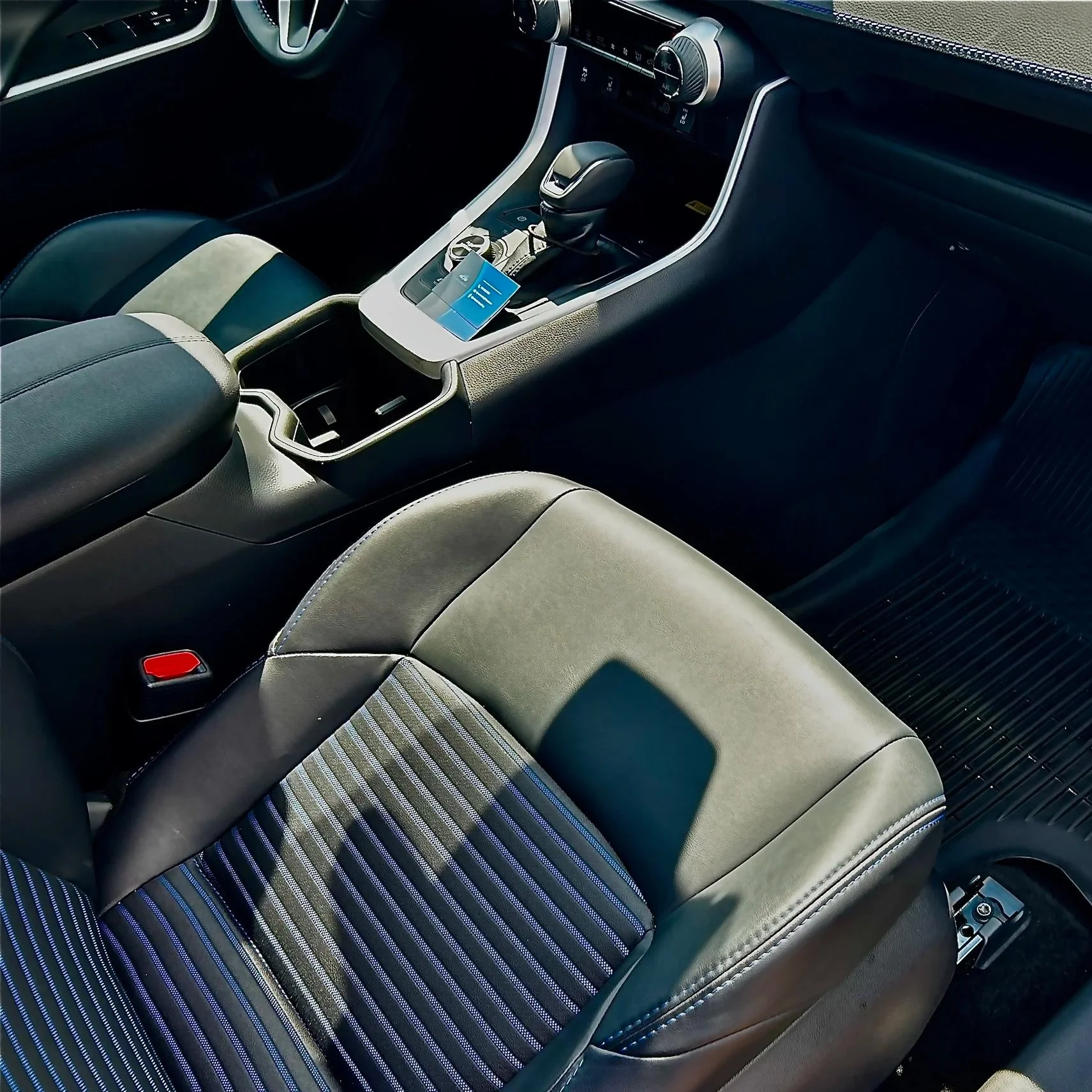 Car interior with black and blue striped seats, gear shift, and center console.
