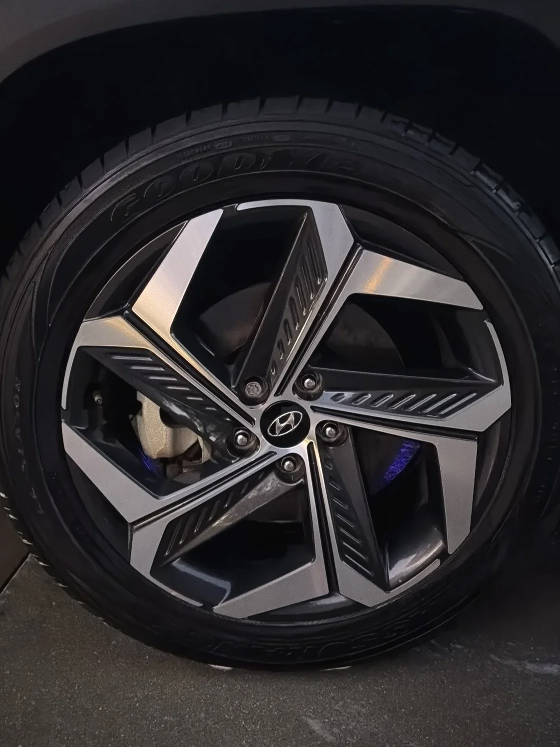 Close-up of a car wheel with a black and silver rim, Hyundai logo at the center, and a mounted tire.