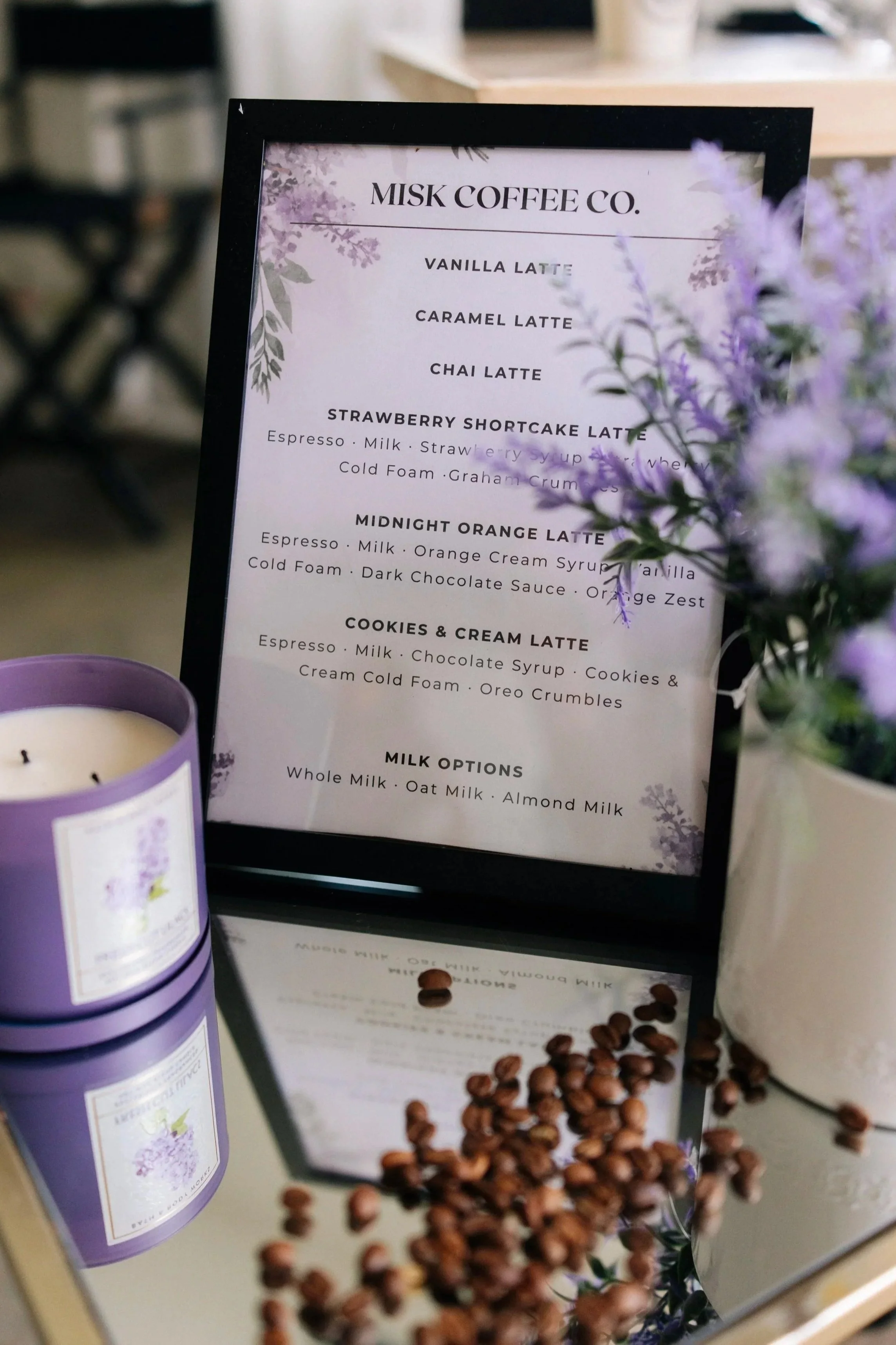 A menu board from Misk Coffee Co. listing various latte options, including Vanilla Latte, Caramel Latte, Chai Latte, Strawberry Shortcake Latte, and Midnight Orange Latte.