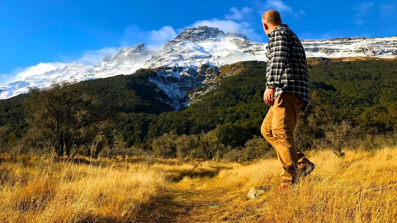 A person standing on a grassy track facing Mount Earnslaw, suggesting steadiness and a new beginning