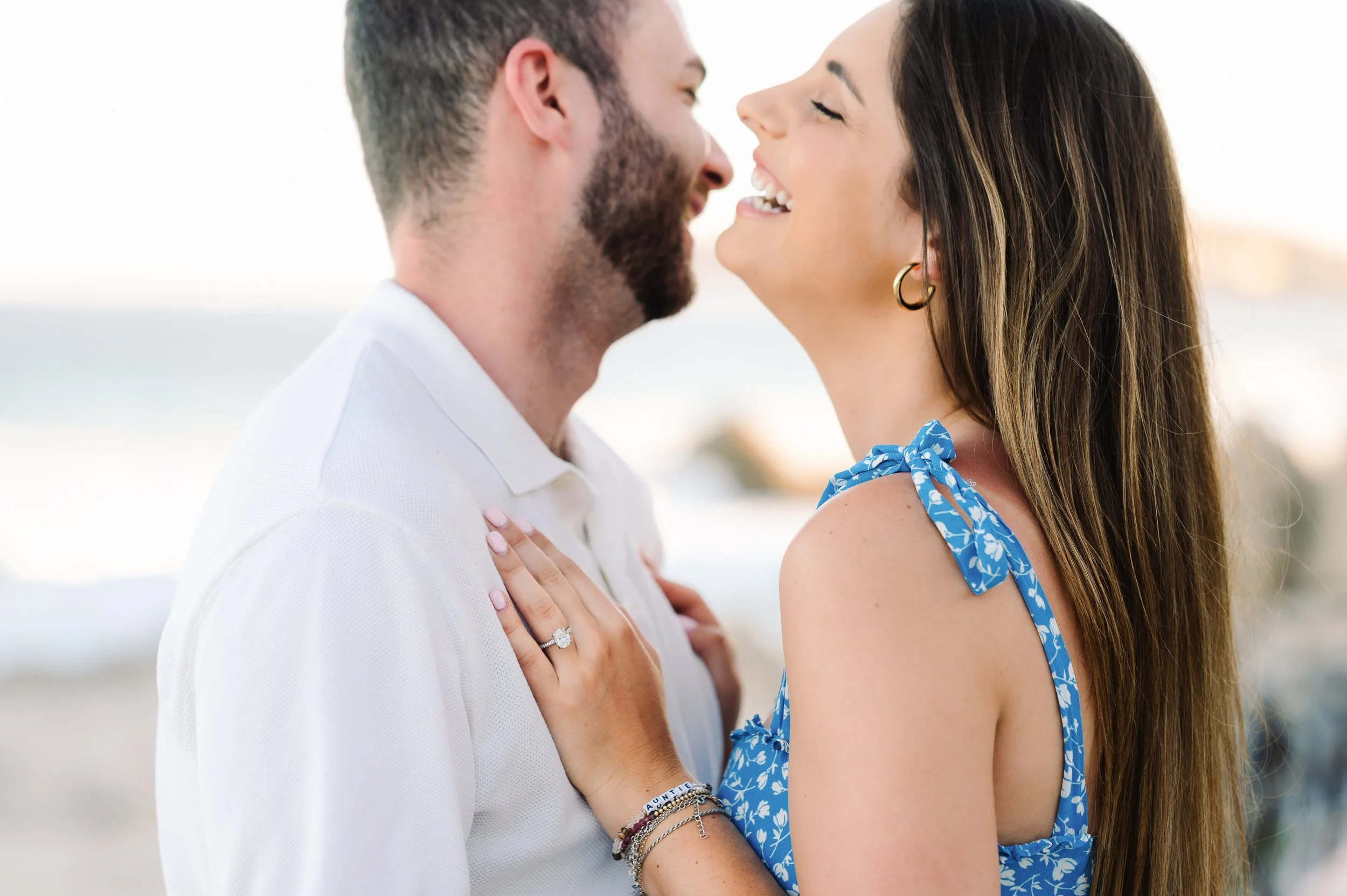 Una pareja feliz riendo y acariciándose en la playa al atardecer.