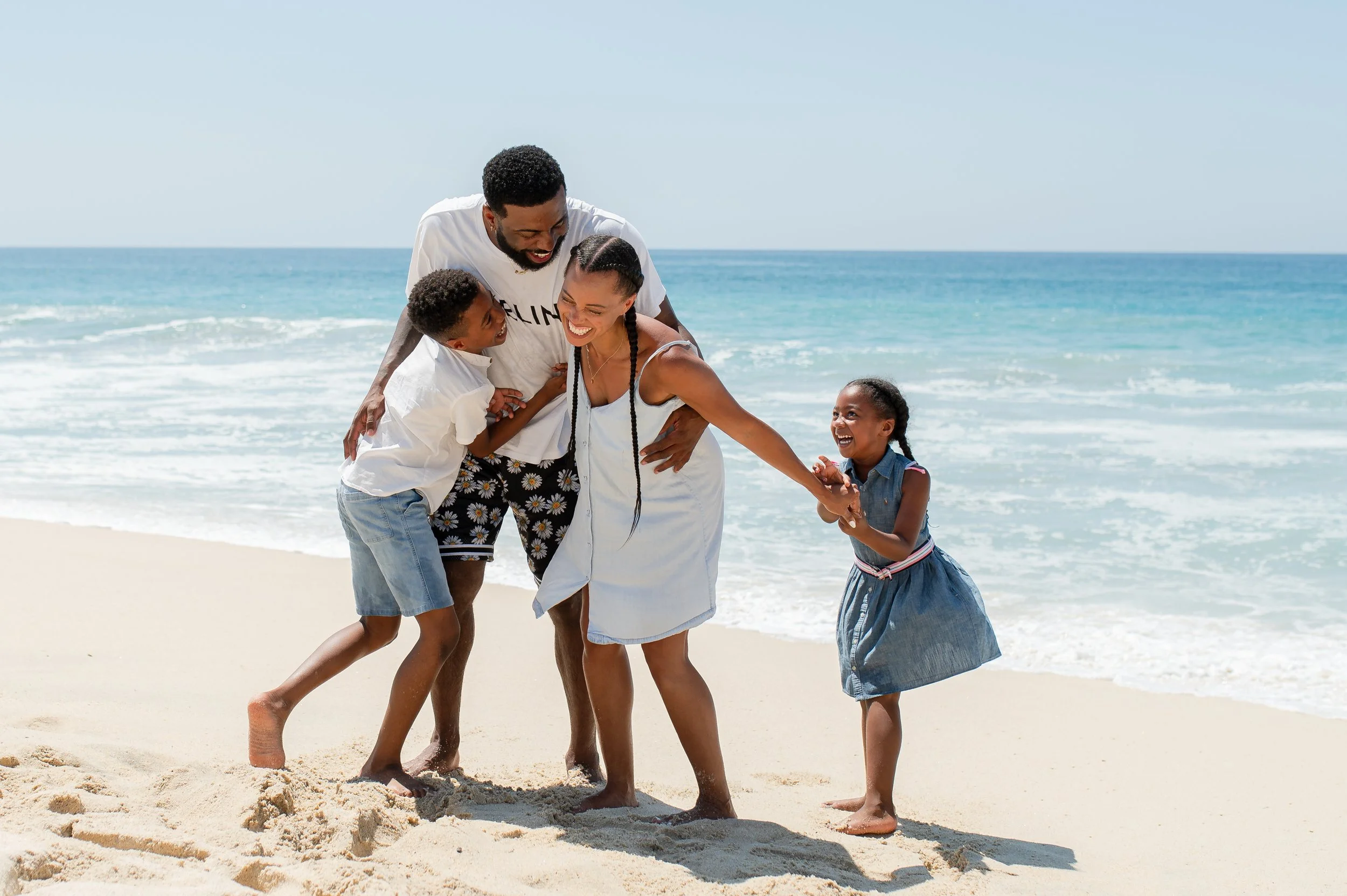 Familia disfrutando y riendo en la playa junto al mar