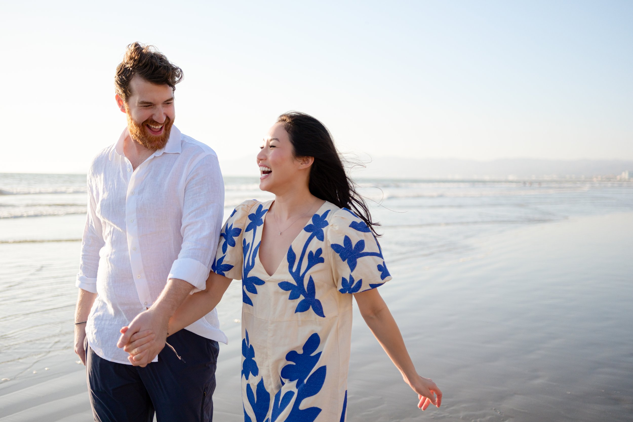 una pareja feliz caminando por la orilla del mar en la playa, sonriendo y disfrutando del día soleado