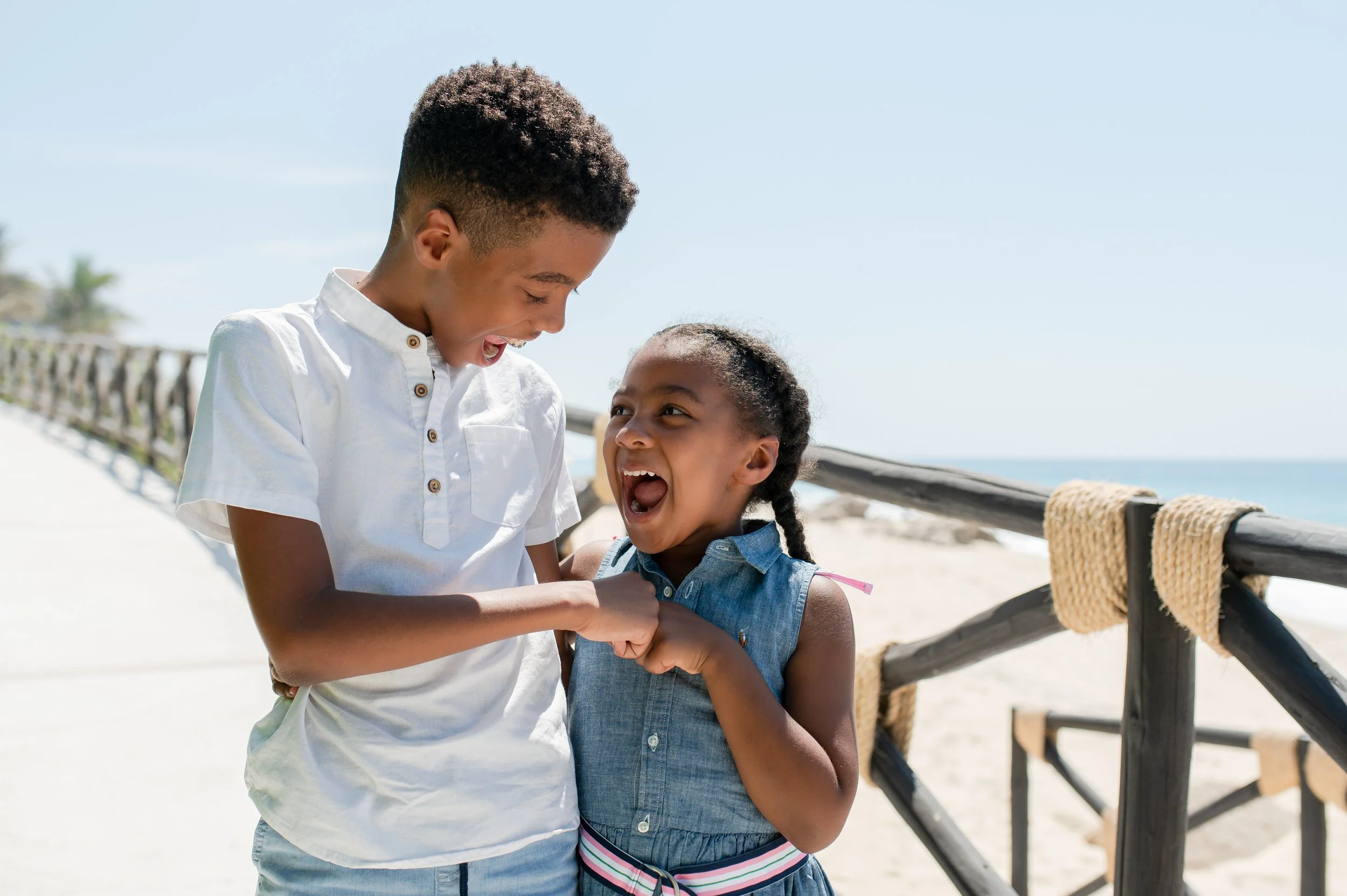 Un niño y una niña pequeños jugando y riendo juntos en la playa, mostrando diversión y amistad.