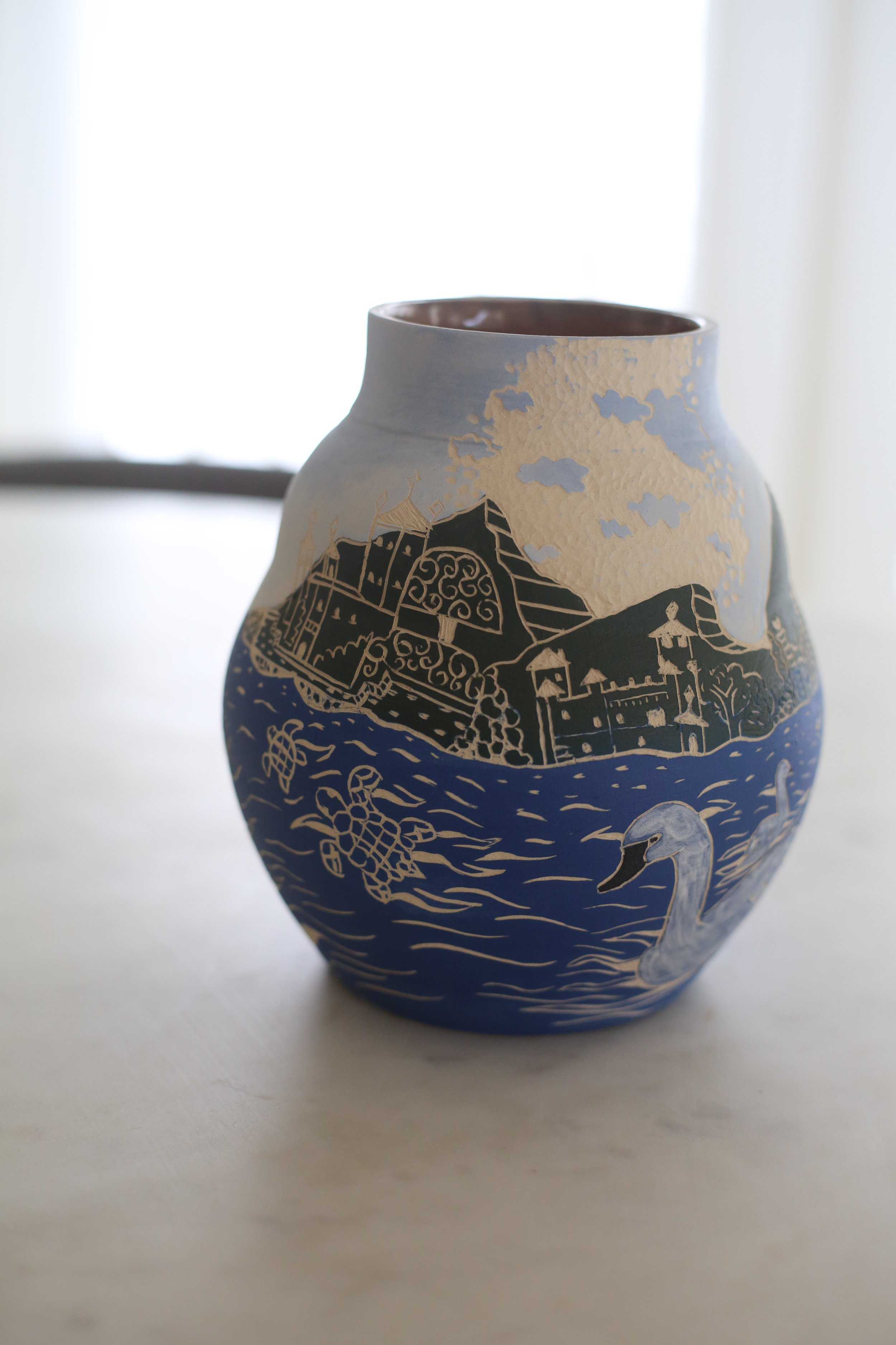 Decorative ceramic vase by Amy Ambrose with a sgraffito illustration of Lake Como featuring a swan.