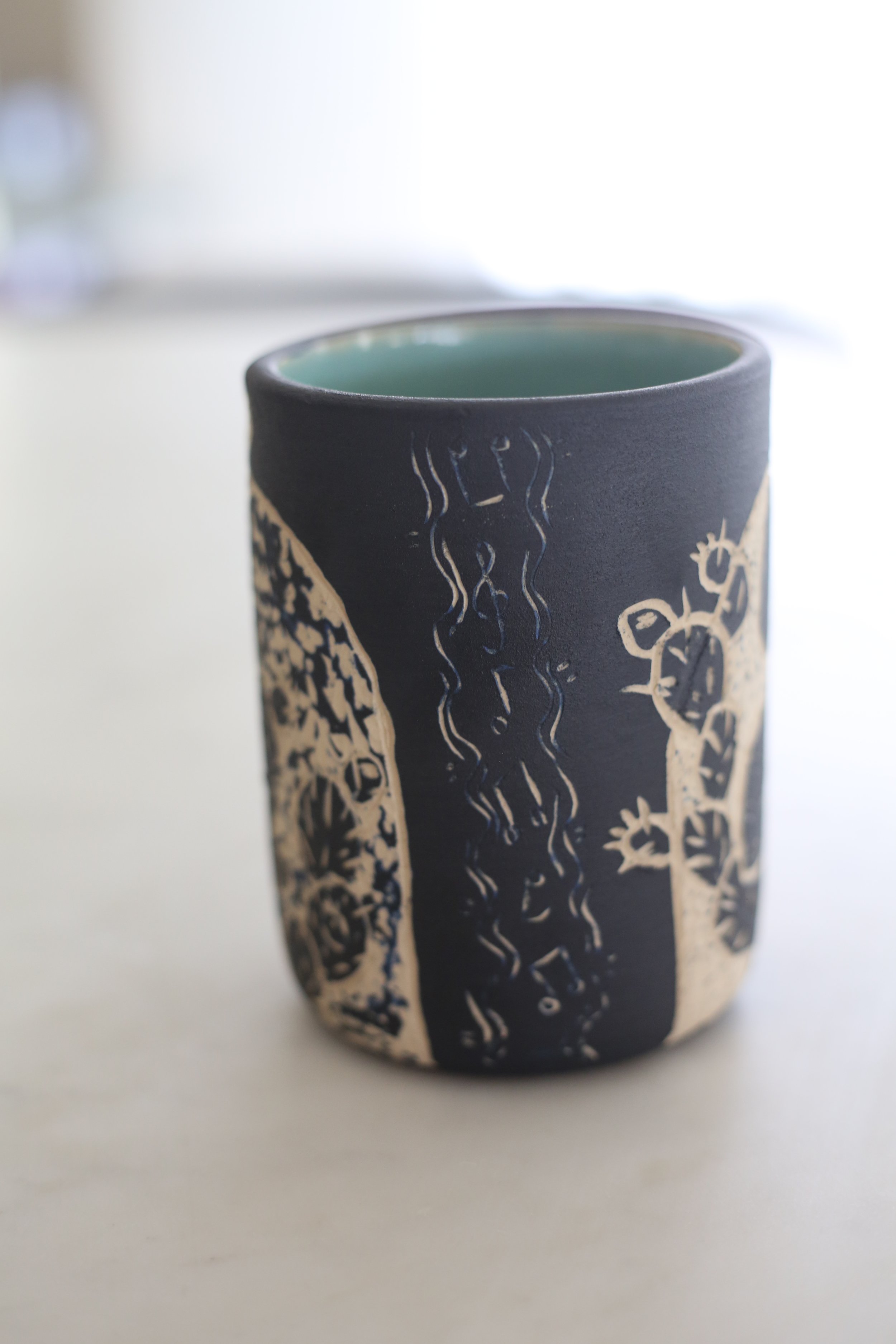 A ceramic tumbler by Amy Ambrose with sgraffito art of music notes.