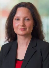 Professional woman with shoulder-length dark hair wearing a black blazer and red top