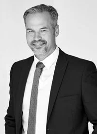 Black and white portrait of a smiling man in a suit and tie.