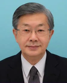 Portrait of a middle-aged Asian man in a black suit, white shirt, and tie, against a blue background.