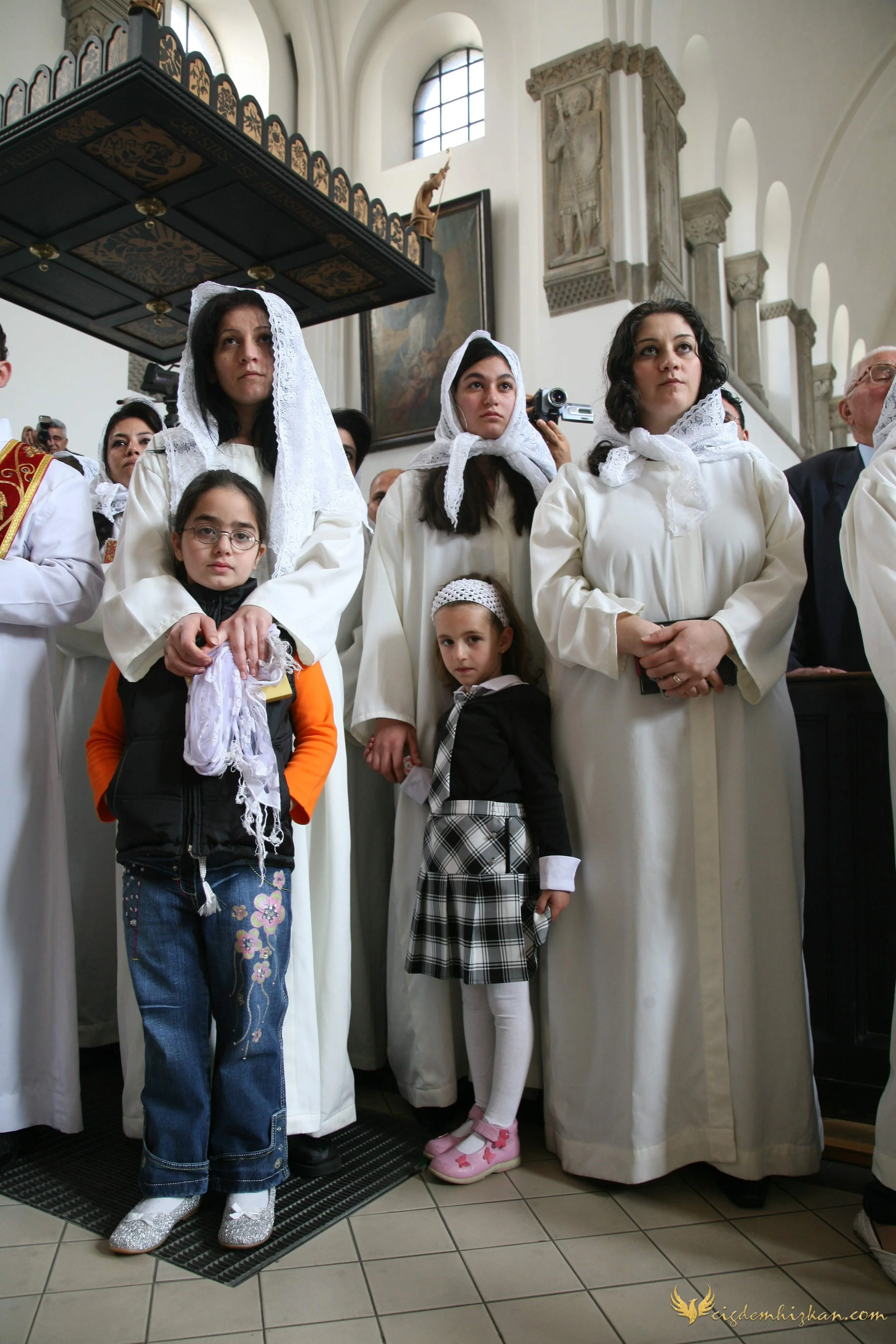 Süryani Ortodoks geleneğinde inziva ve dua anı. Kilise mekânı, ritüel sessizliği ve içsel yoğunluk. Başörtülü Süryani kız çocukları, Hristiyan Süryani geleneği. Mardin, Midyat, Mor Gabriel Manastırı (Deyrulumur).
Syriac Orthodox tradition. Moment of 