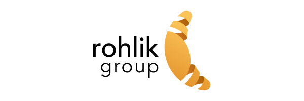 A close-up of a gold-colored pin with a curled design, attached to a black surface.