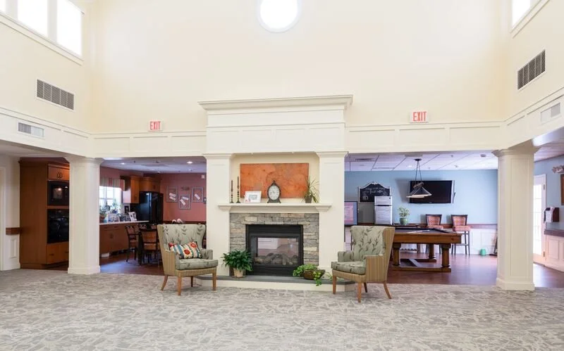 A spacious living room with a fireplace, two armchairs, and a large open area.