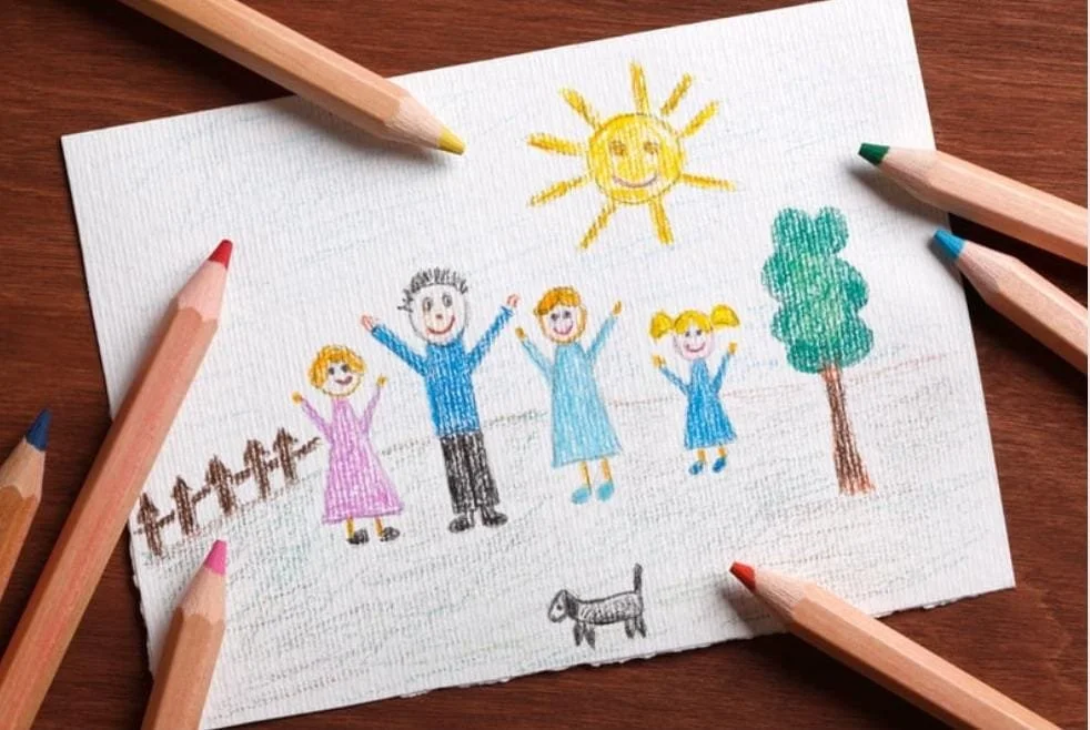 Colorful crayon drawing of a family of five standing outdoors under the sun, with a tree, a dog, and a fence nearby.