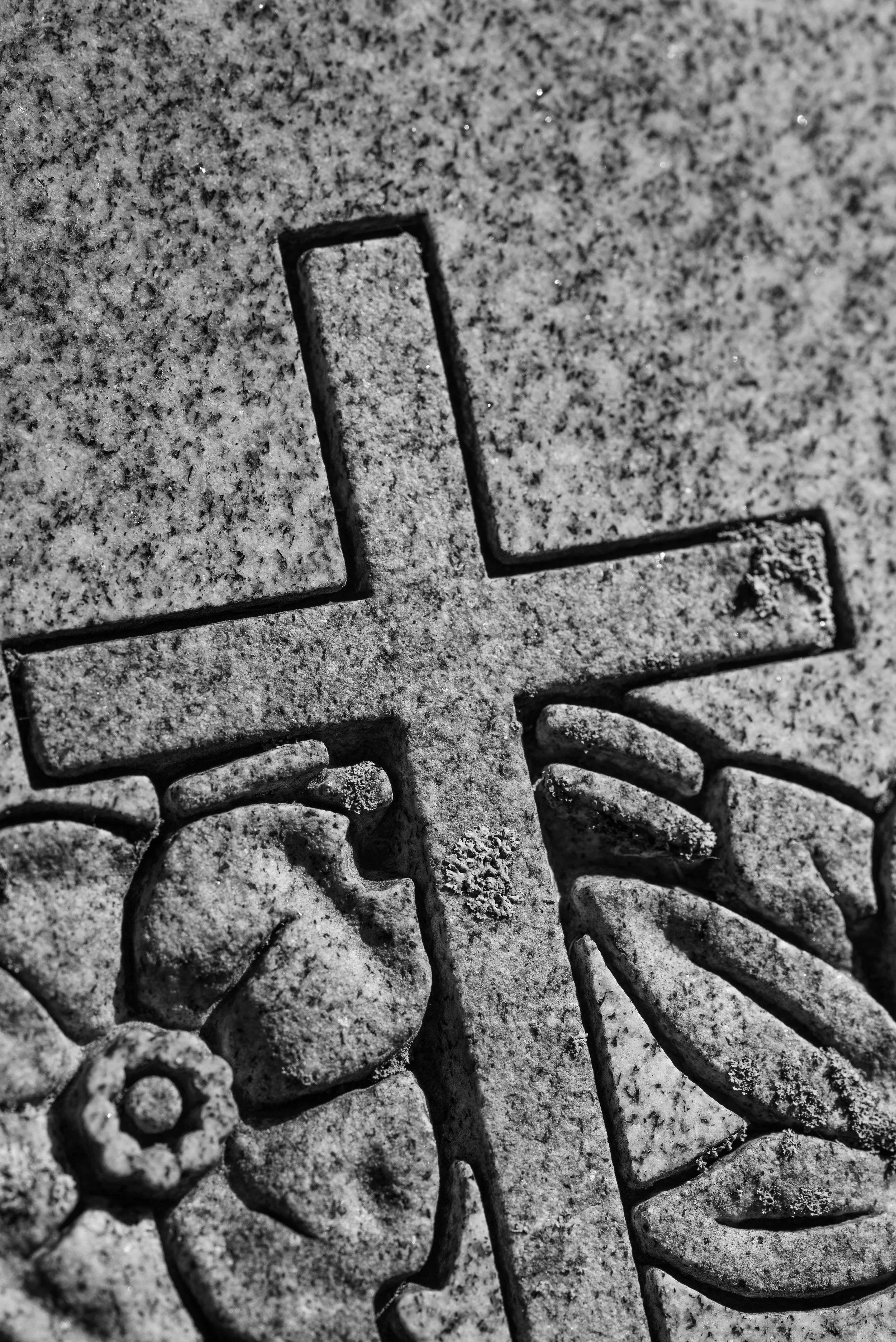 Close-up of a carved stone cross with floral designs in black and white.
