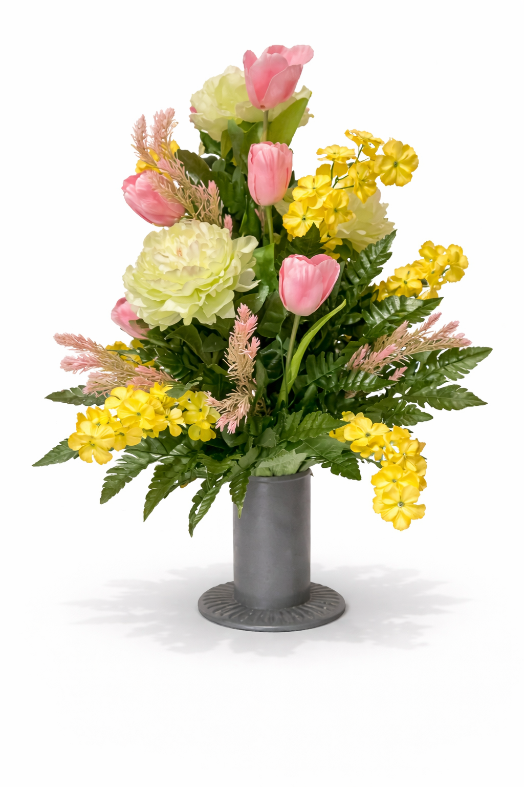A colorful floral arrangement in a gray vase with pink tulips, yellow flowers, green leaves, and pink accents.