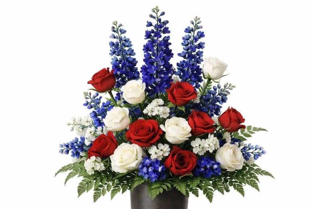 A floral arrangement with red, white, and blue flowers in a black vase.