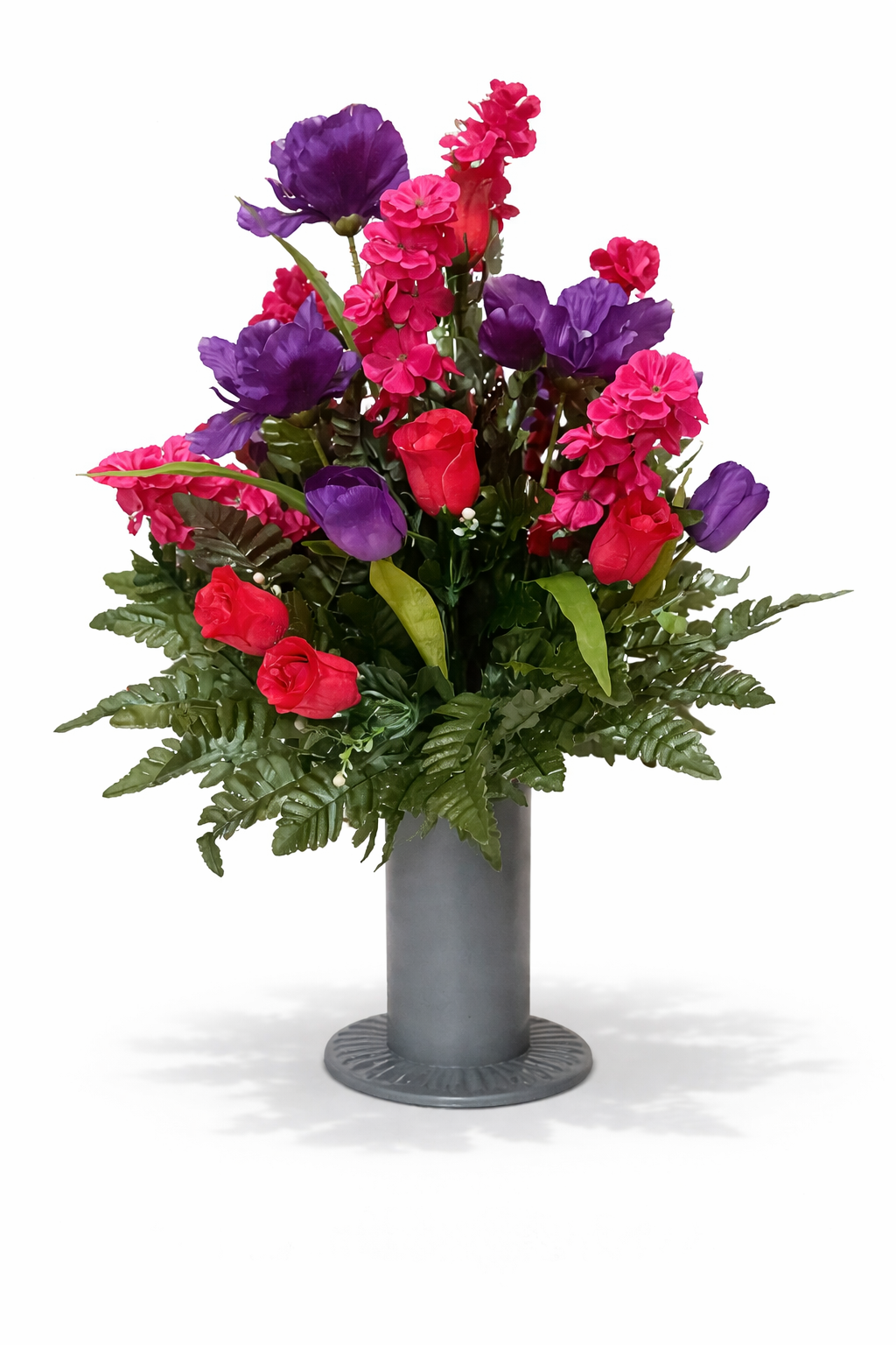 A colorful flower arrangement in a tall, gray vase, featuring purple, pink, and red flowers with green leaves and fern accents.