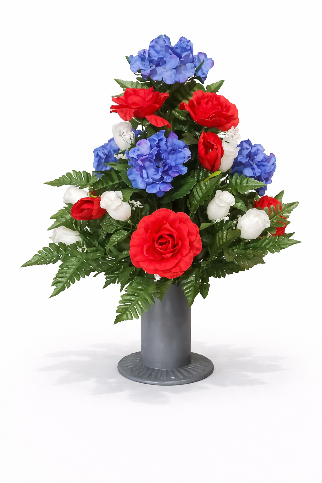 A bouquet of red, white, and blue artificial flowers arranged in a silver vase.
