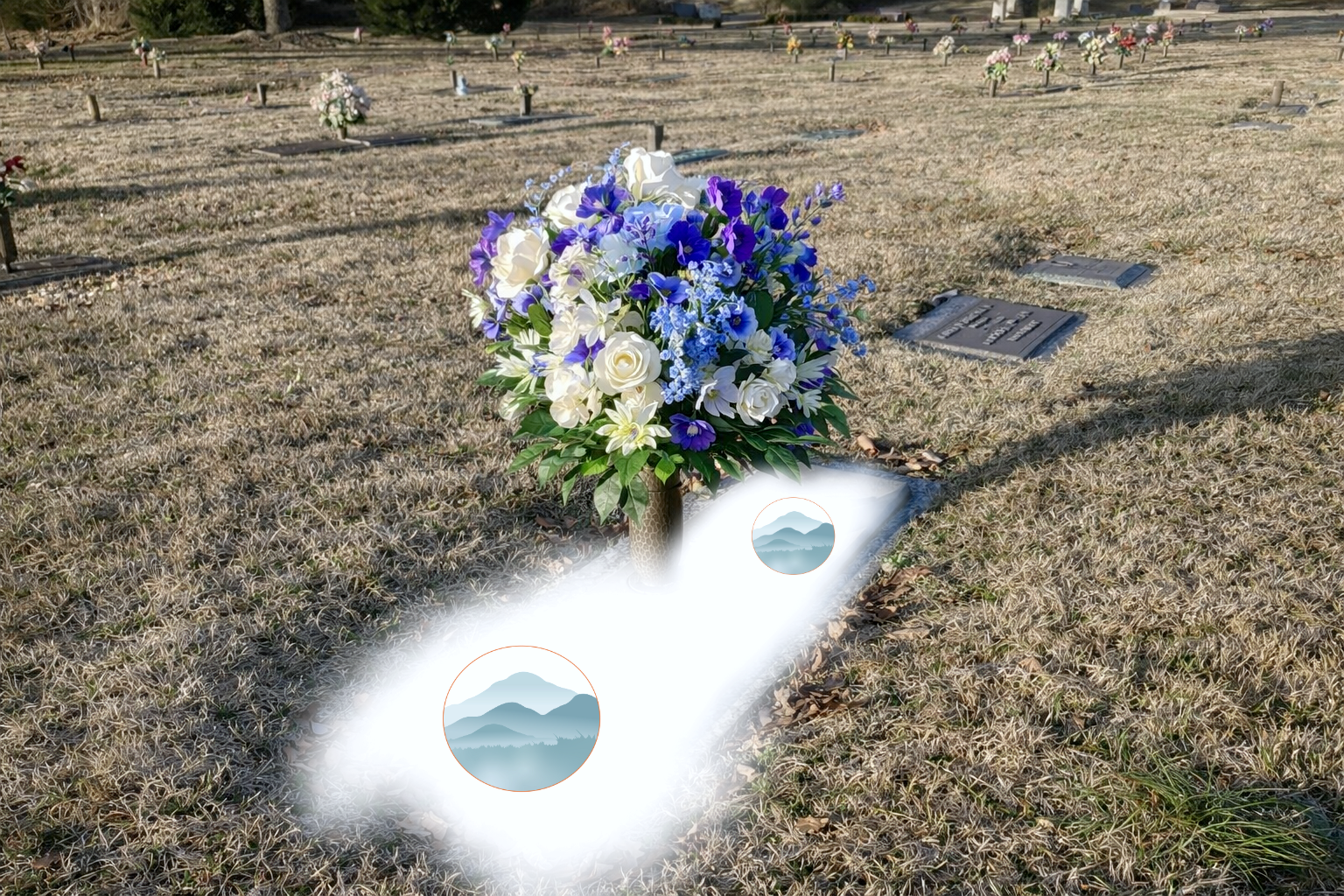 Gravestone in a cemetery decorated with a large bouquet of white, purple, and blue flowers, with other gravestones visible in the background.